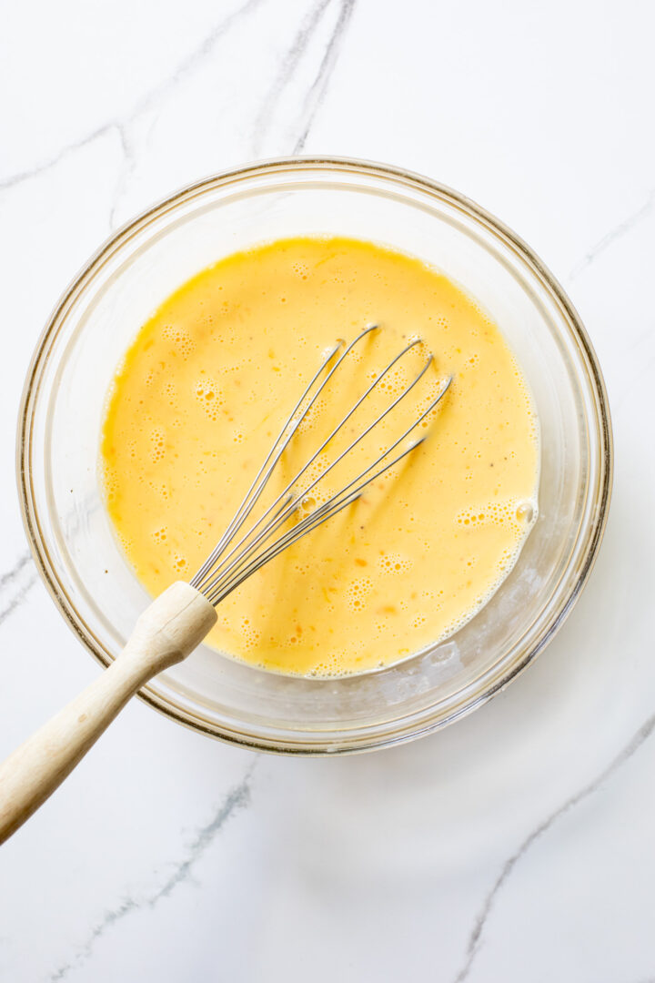 whisked eggs with cream in a glass bowl.