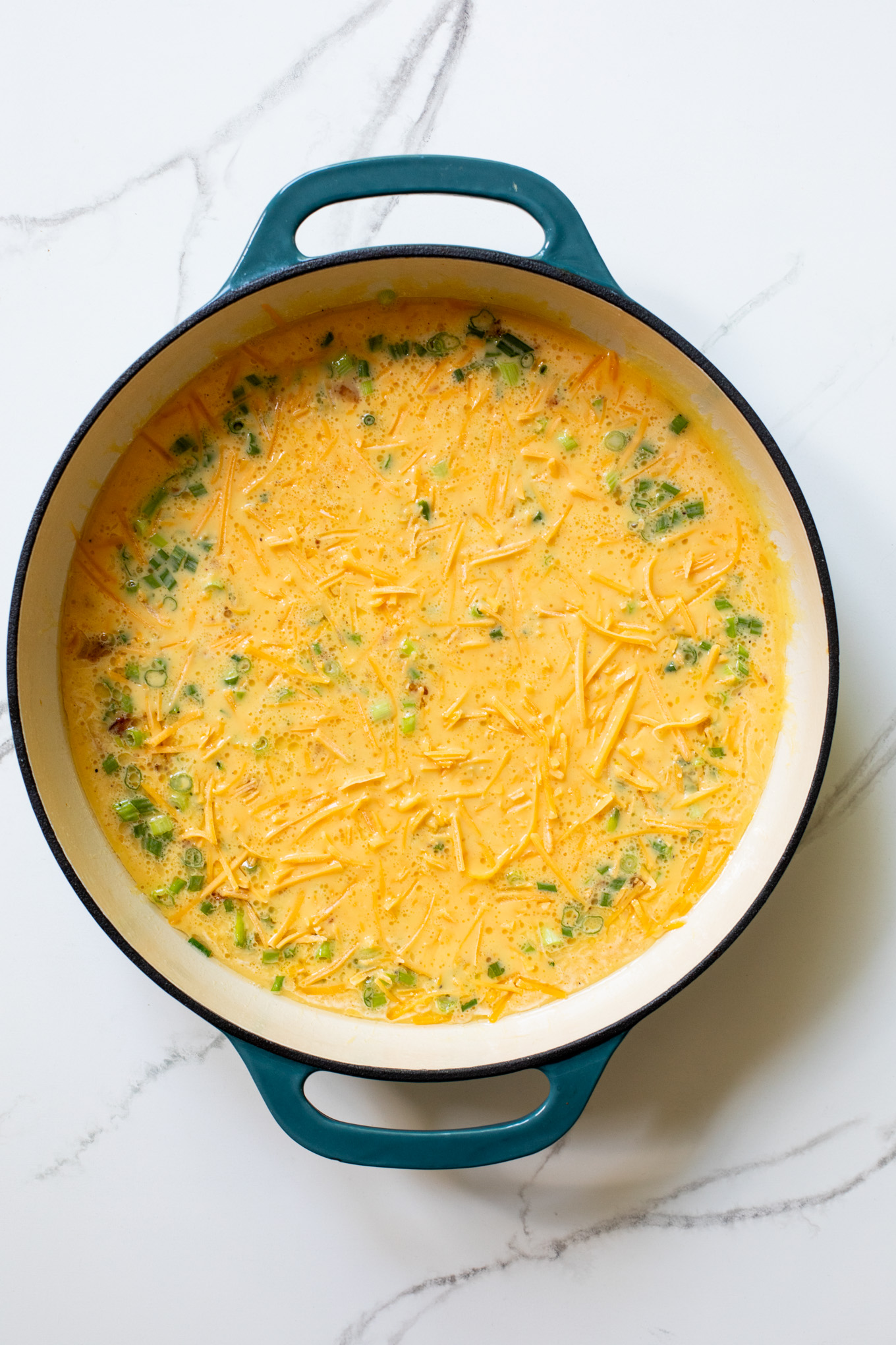 egg mixture in a cast-iron skillet topped with cheddar cheese.