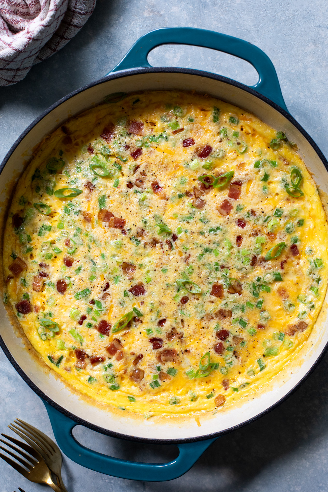 baked breakfast casserole with bacon, cheese, and green onions in a cast iron.