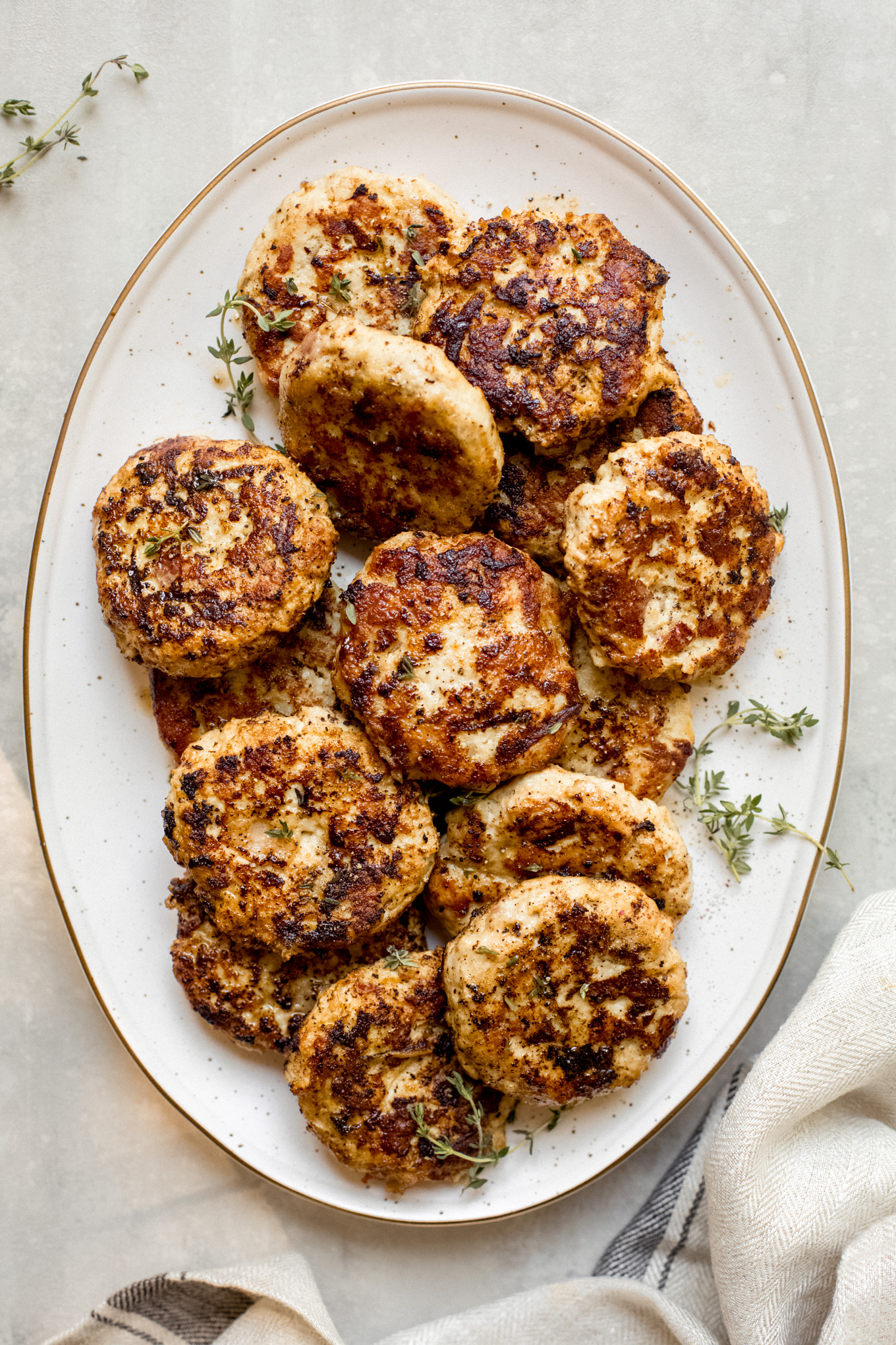 cooked chicken sausage with apples on a platter garnished with fresh thyme.