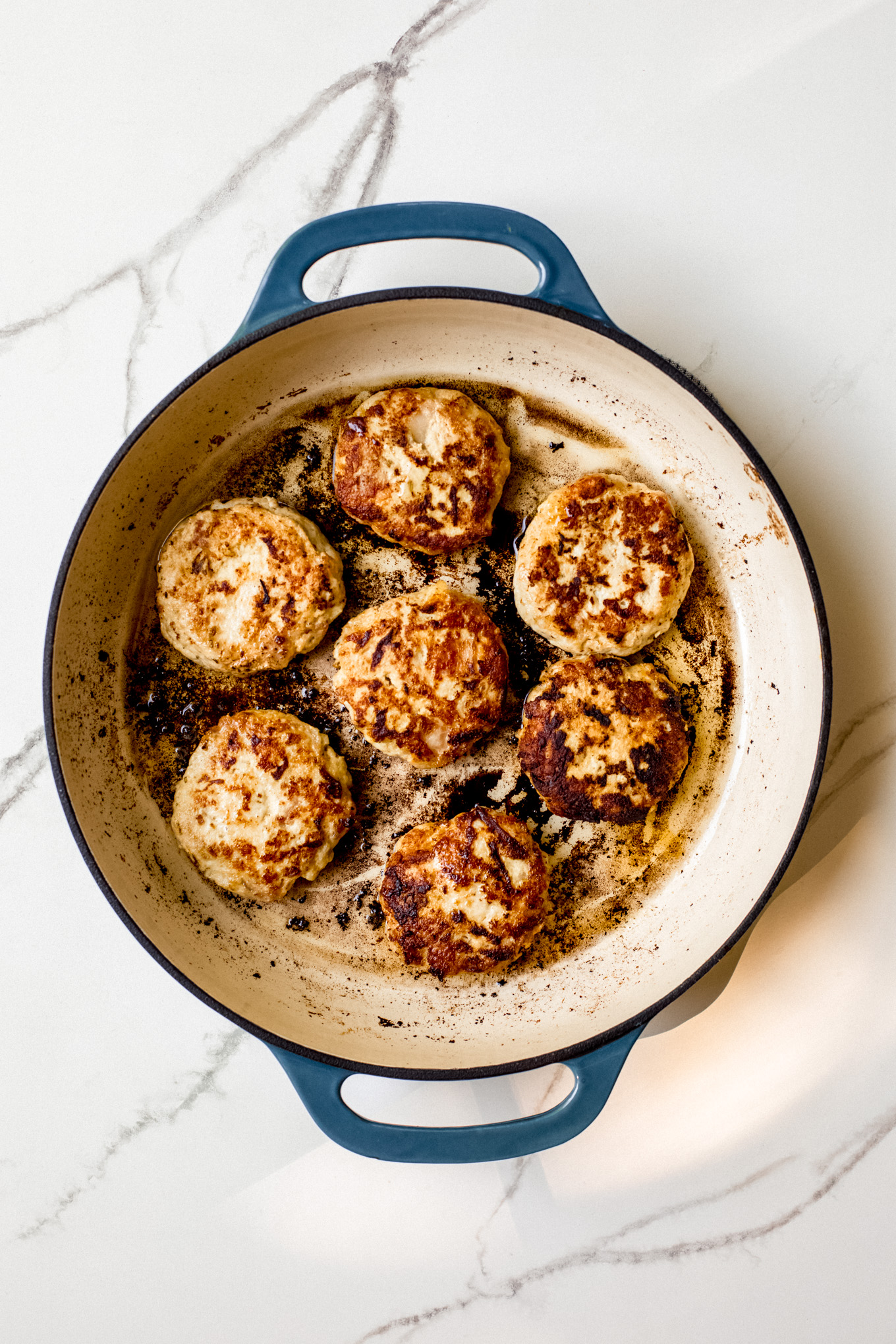 cooked chicken patties in a skillet.