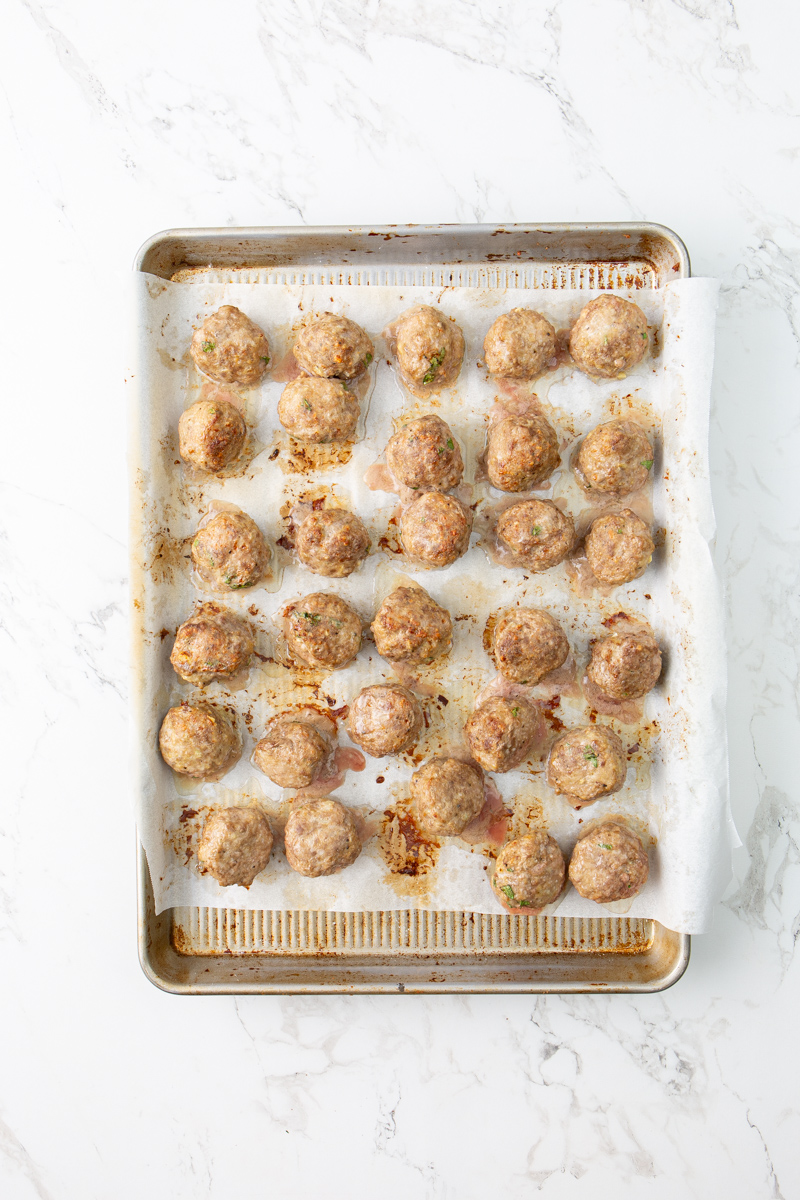 broiled meatballs on a baking sheet pan.