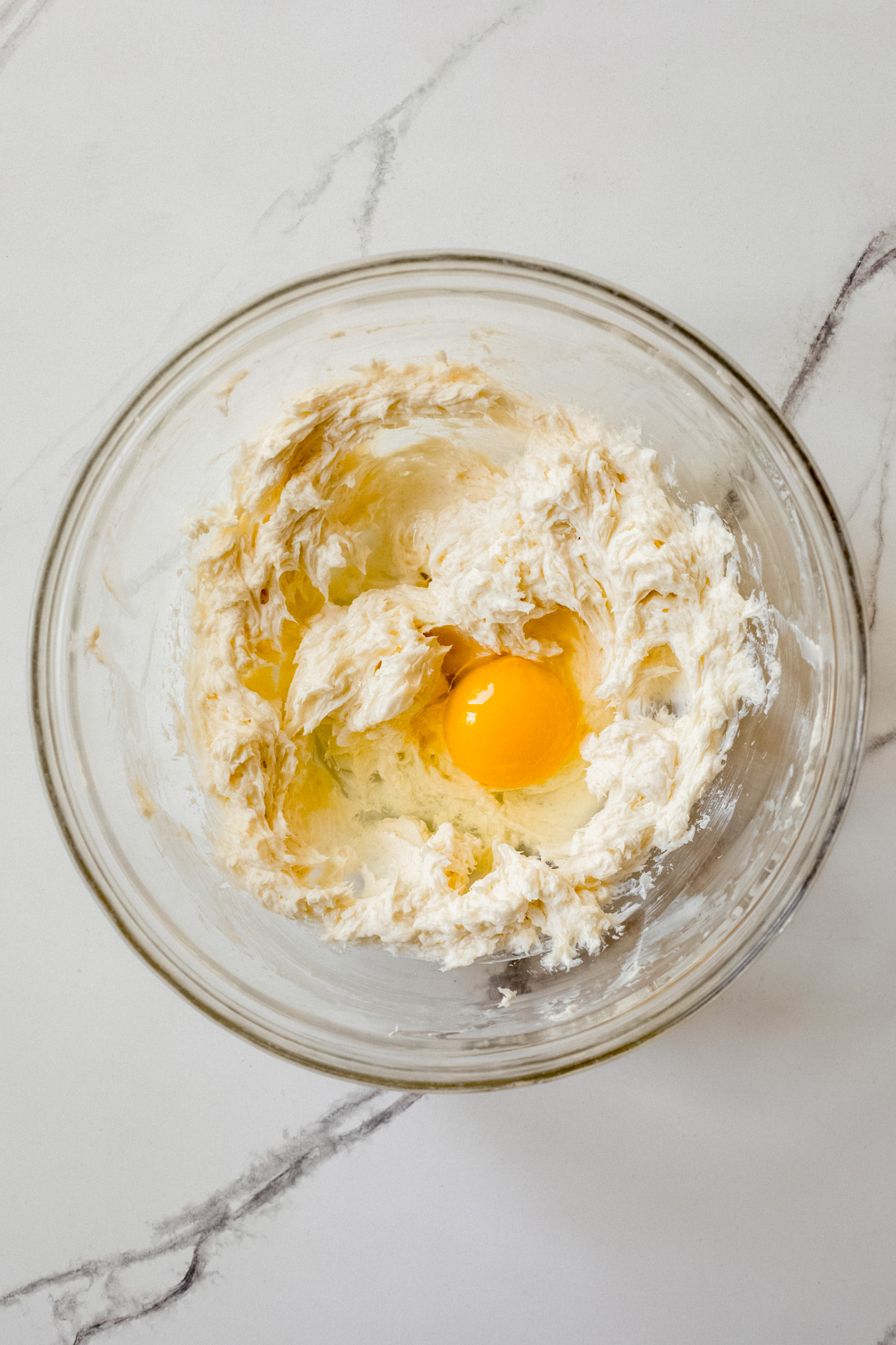 creamed cream cheese with egg in a glass bowl.