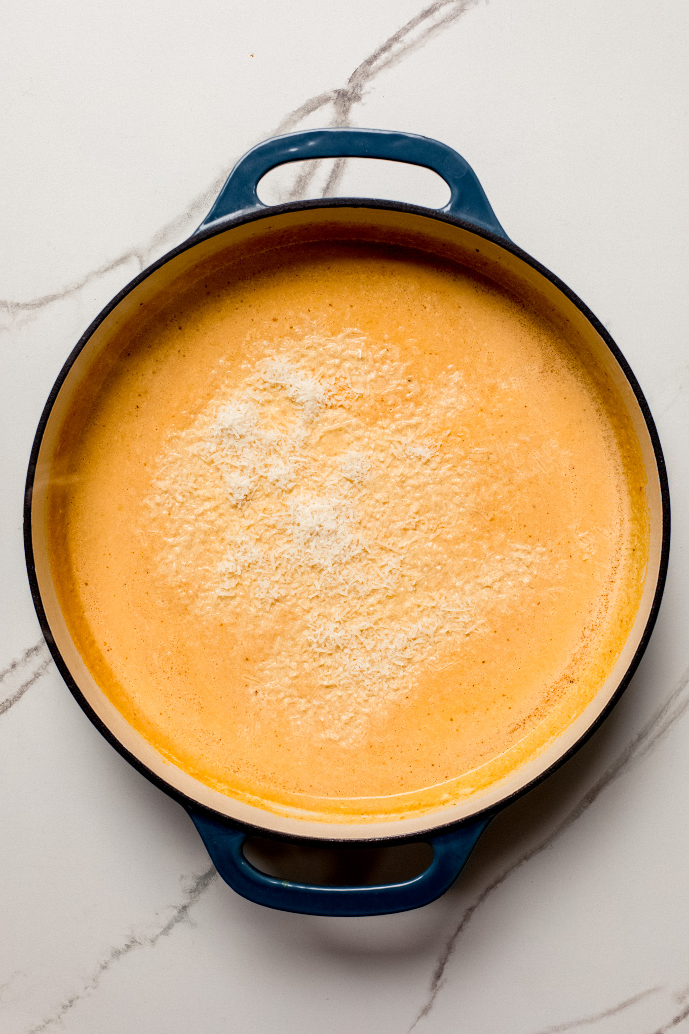 pumpkin sauce in a skillet with parmesan cheese.