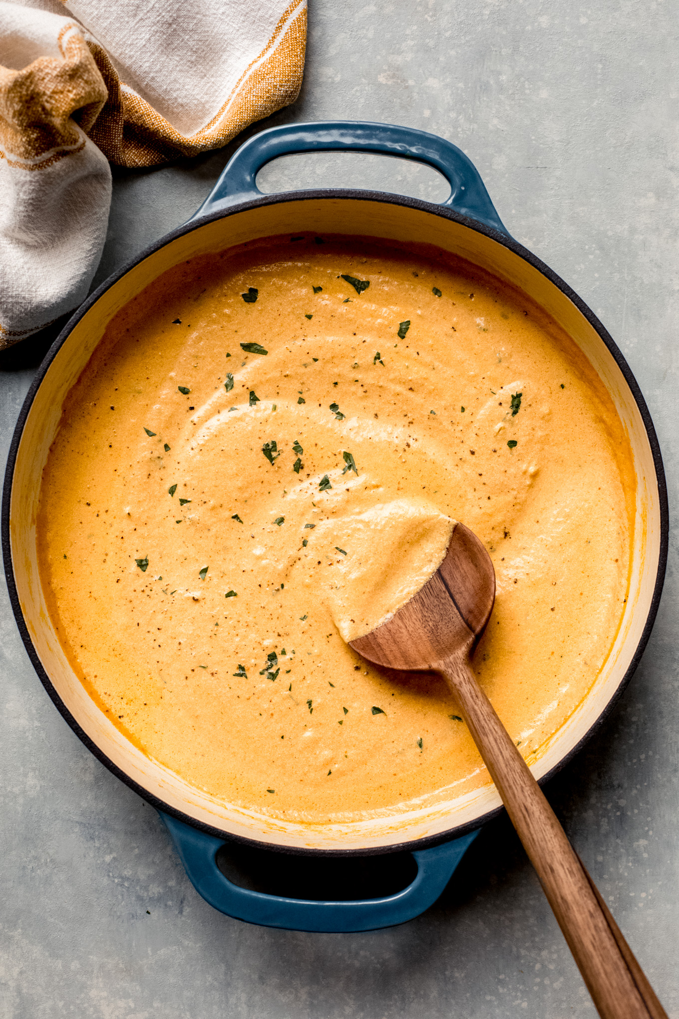 pumpkin cream sauce in a skillet with wooden spoon on the side.