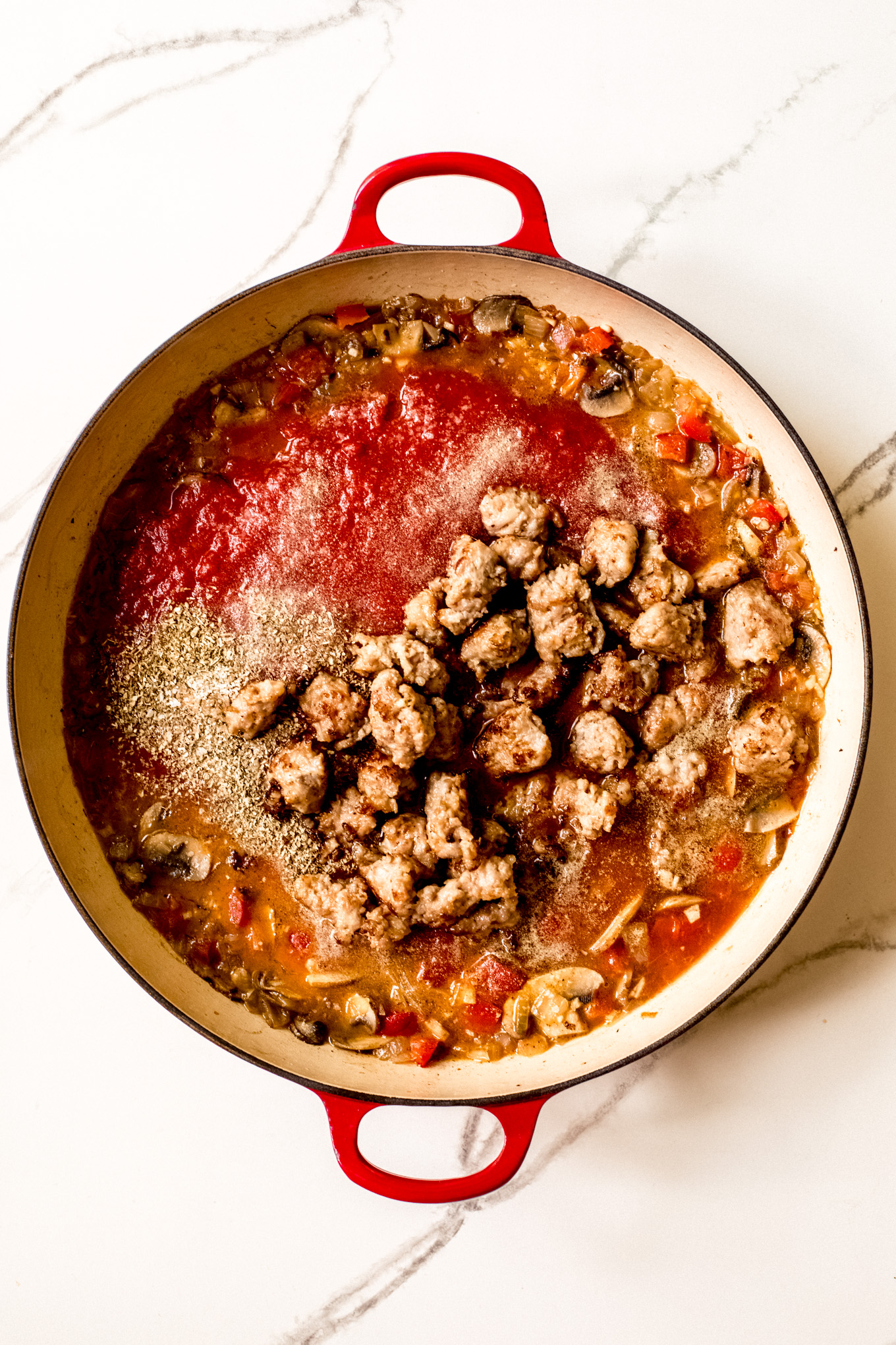 tomato sauce with cooked sausage in a pan.