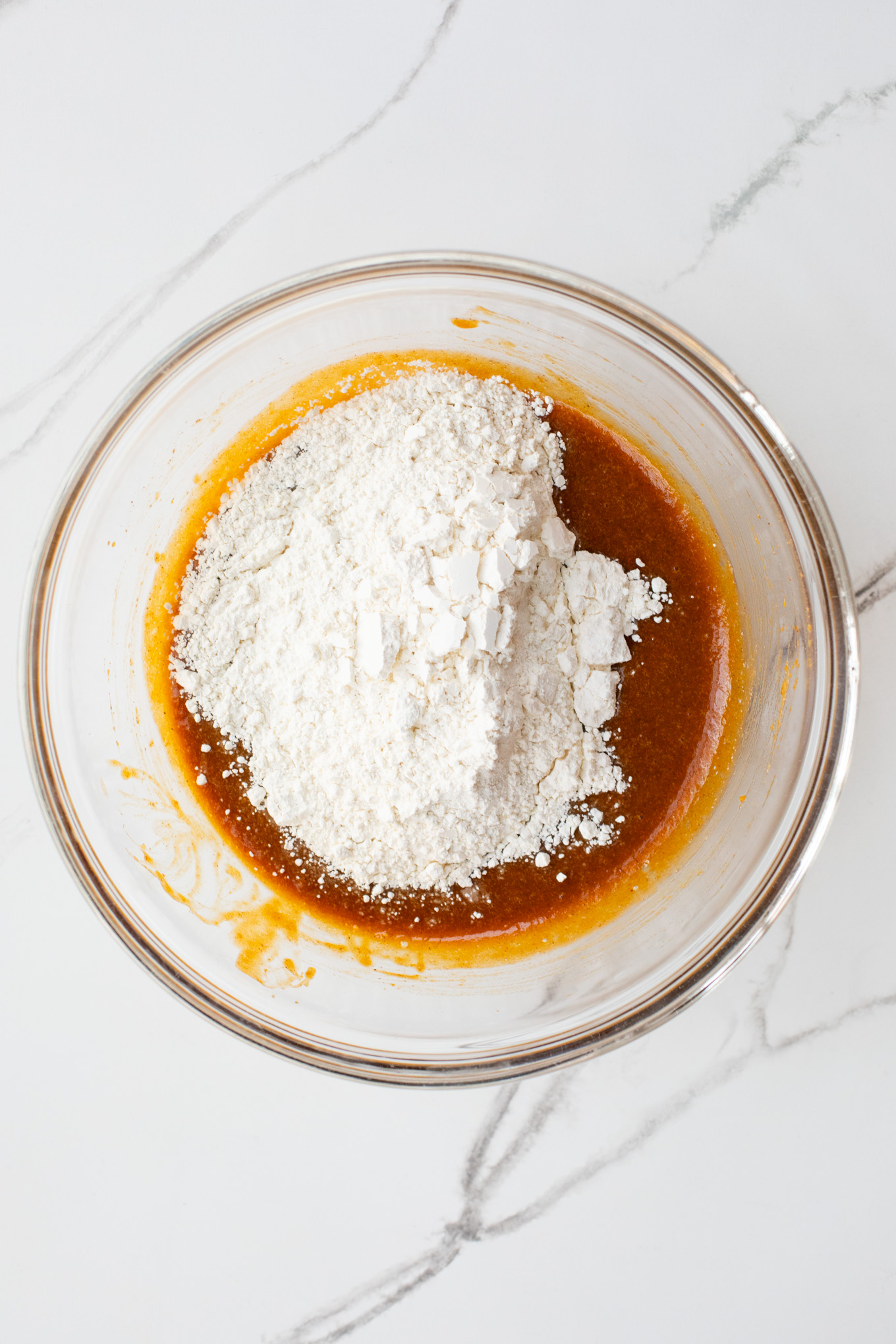 flour with wet ingredients in a glass bowl.