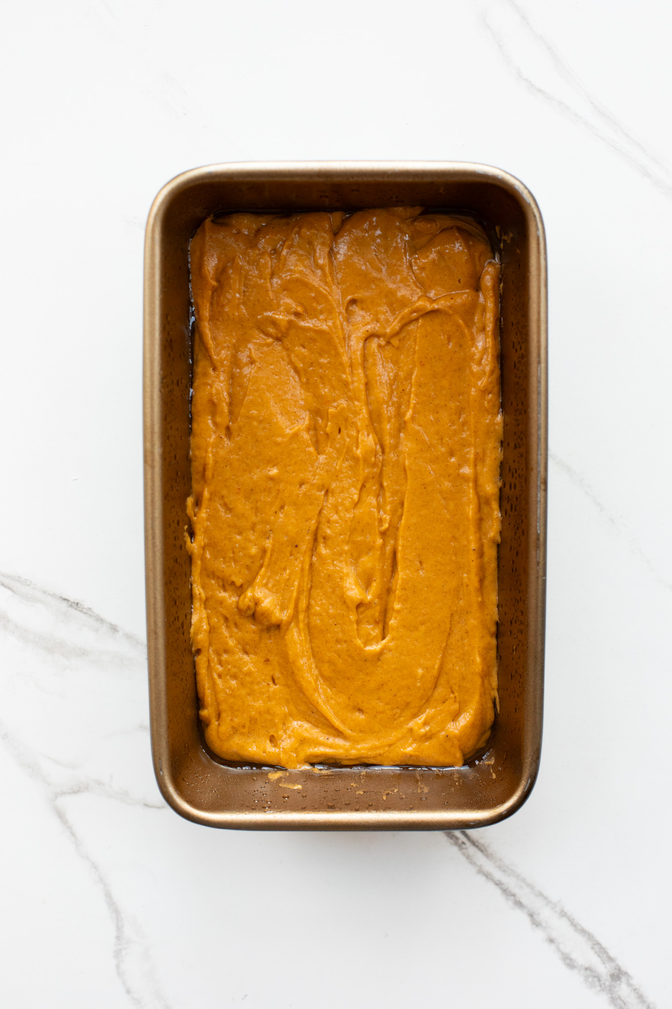 pumpkin bread batter in a loaf pan.