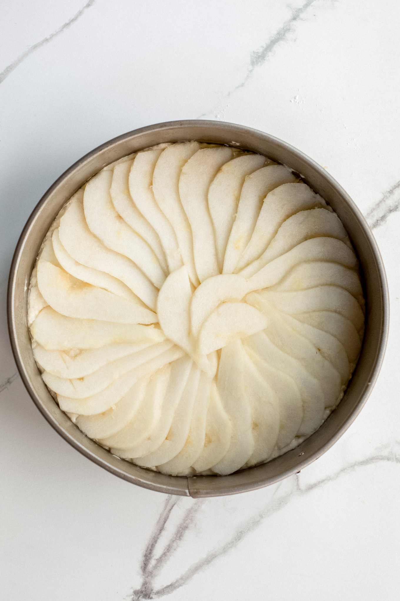 sliced pears layered over cake batter in overlapping pattern.