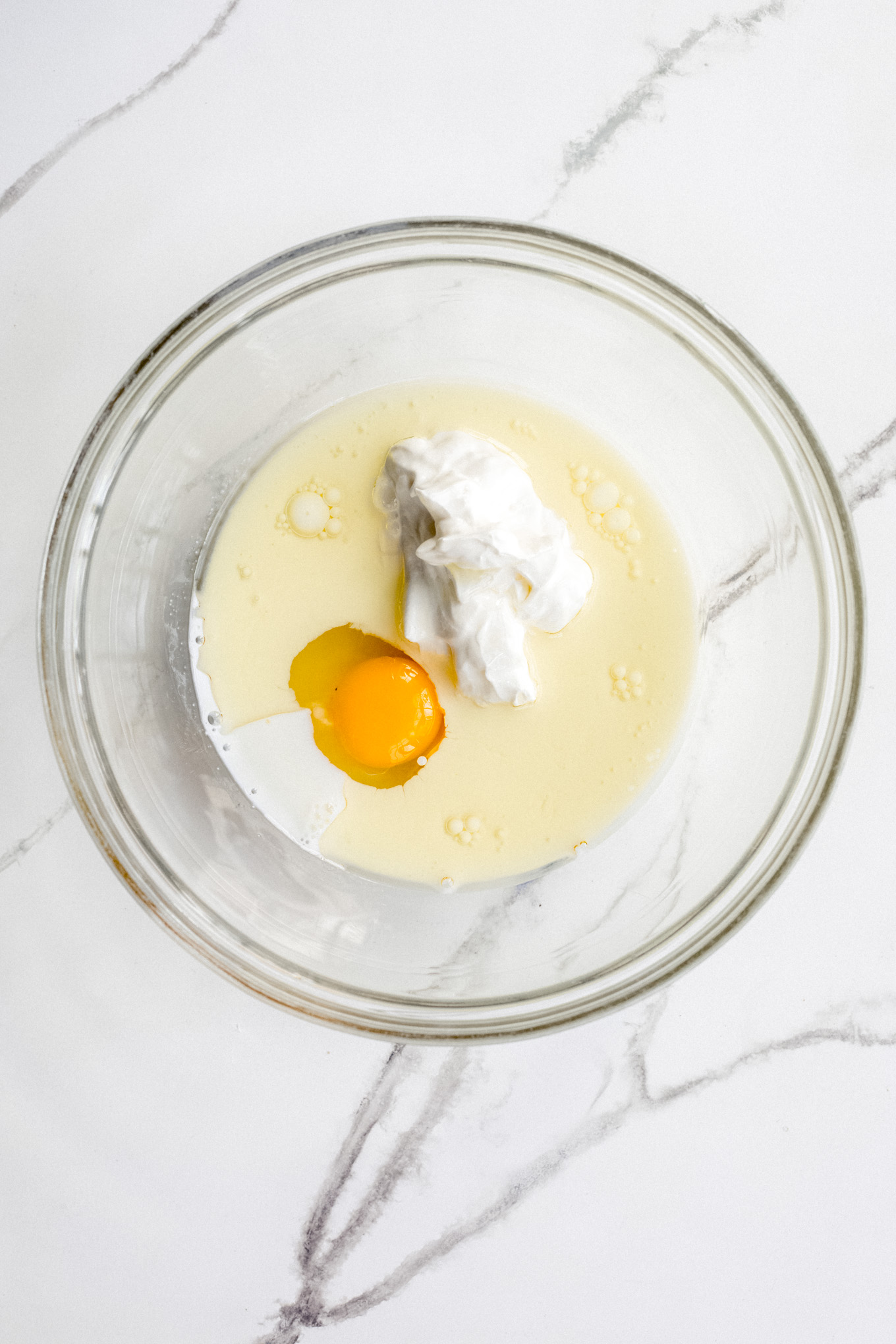 egg, oil, and sour cream in a glass mixing bowl.