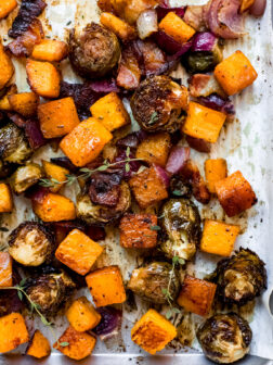 roasted brussels sprouts, butternut squash, on red onion on a sheet pan.