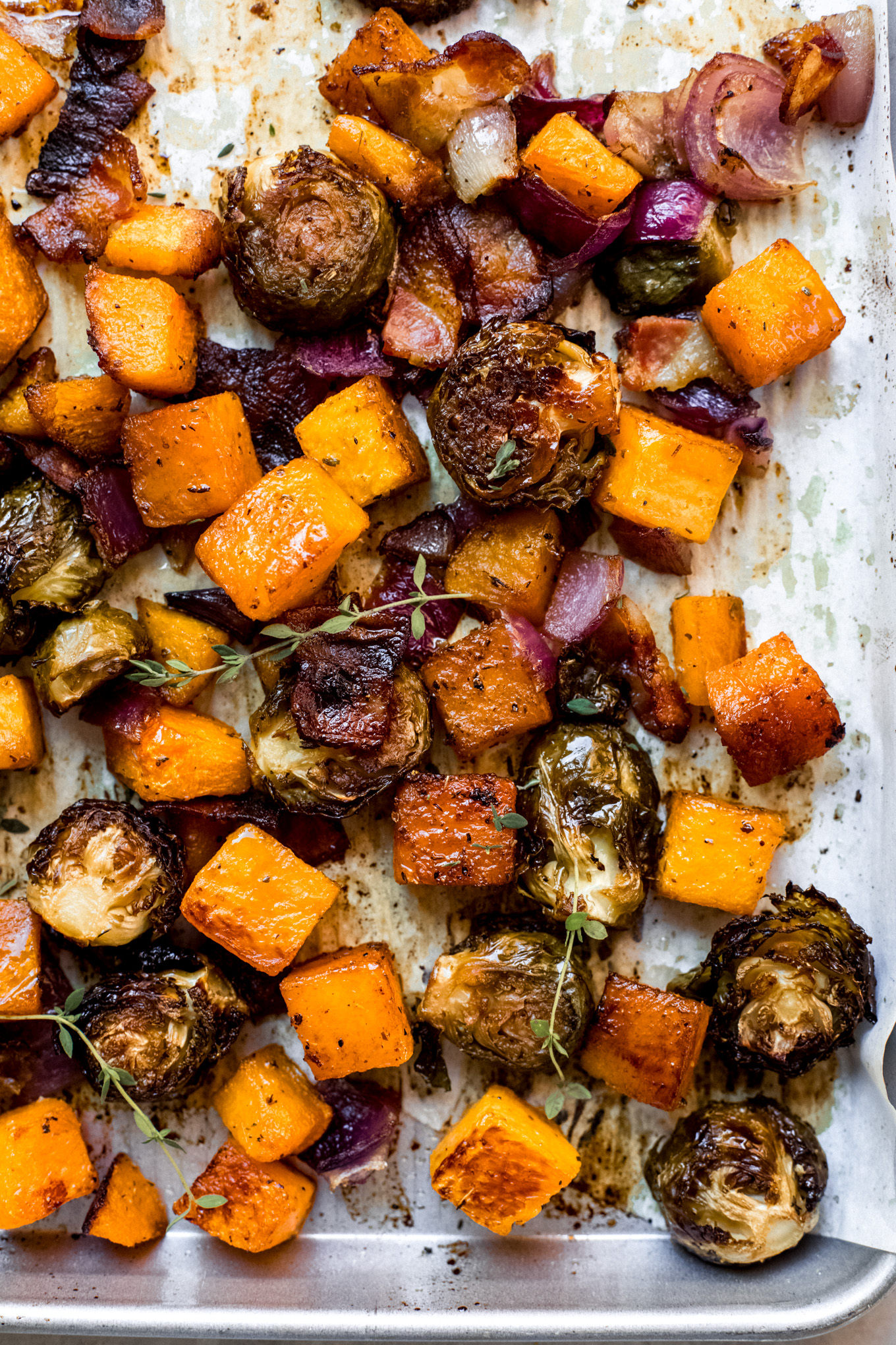 roasted brussels sprouts, butternut squash, on red onion on a sheet pan.