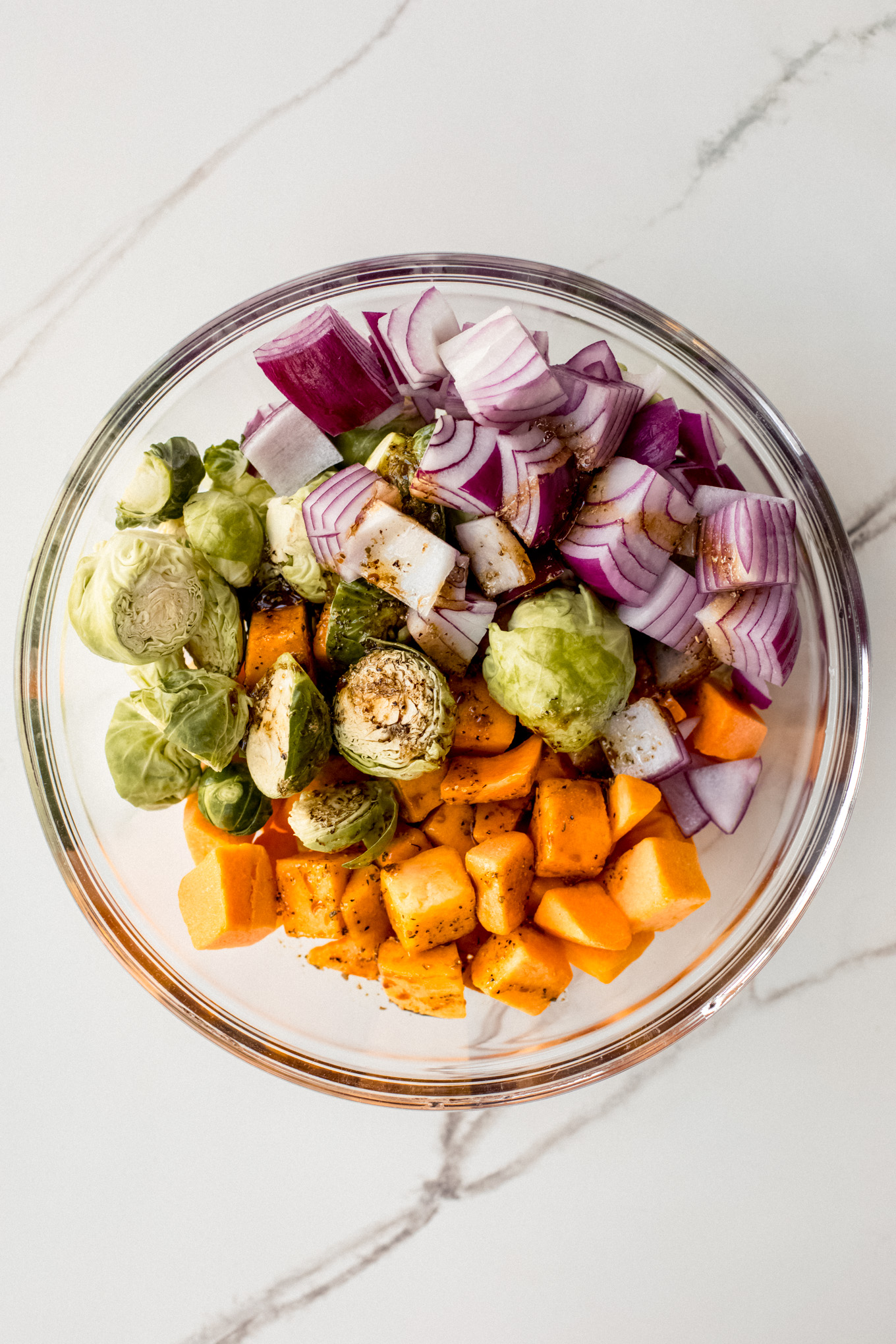 cut up vegetables tossed with a oil in a bowl.