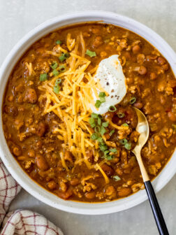 turkey pumpkin chili in a bowl with cheese and green onions.