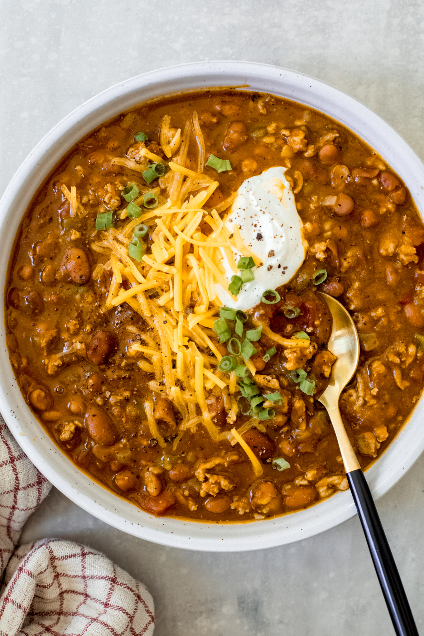 turkey pumpkin chili in a bowl with cheese and green onions.