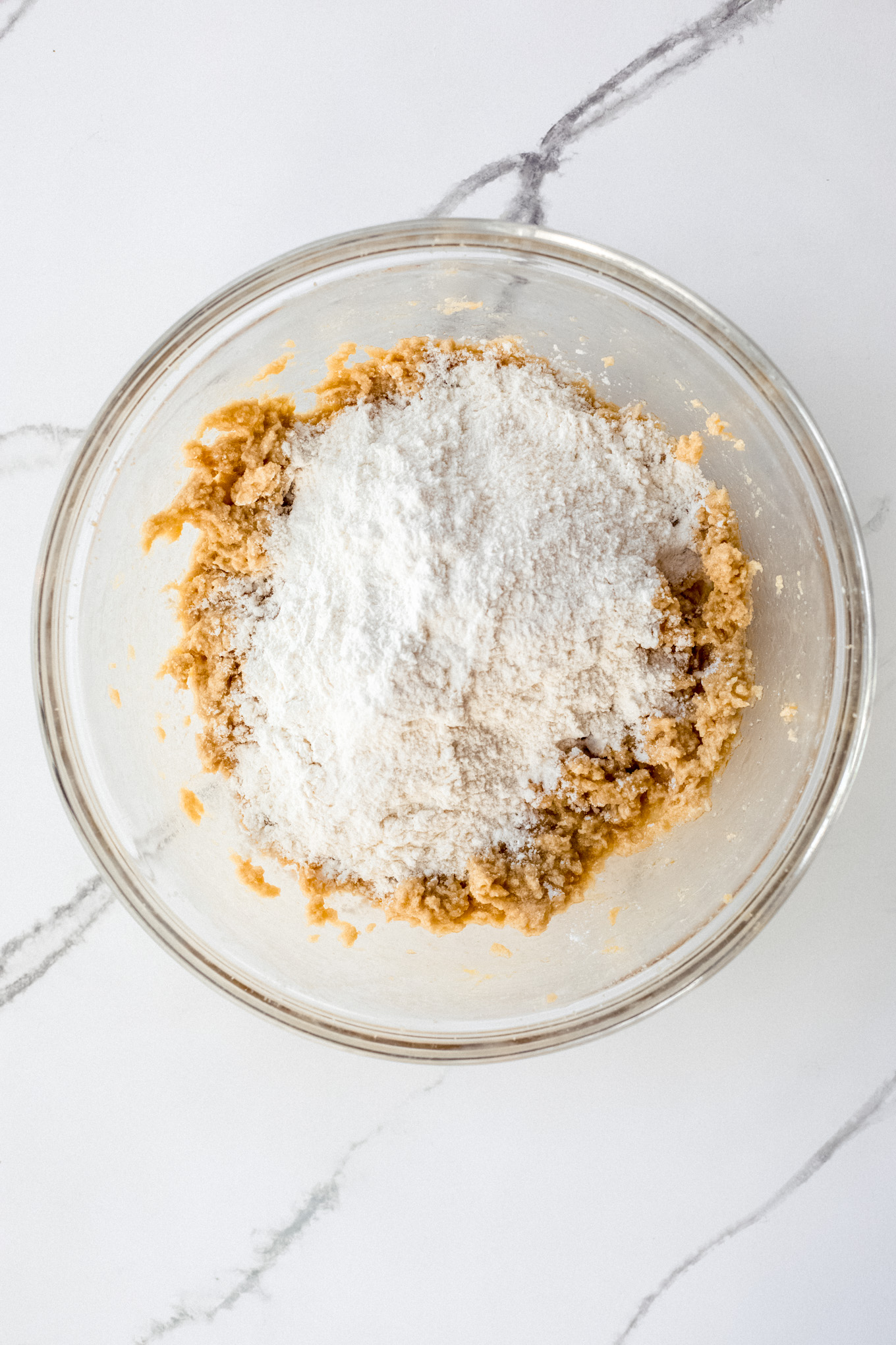 dry ingredients over wet ingredients in a glass bowl.