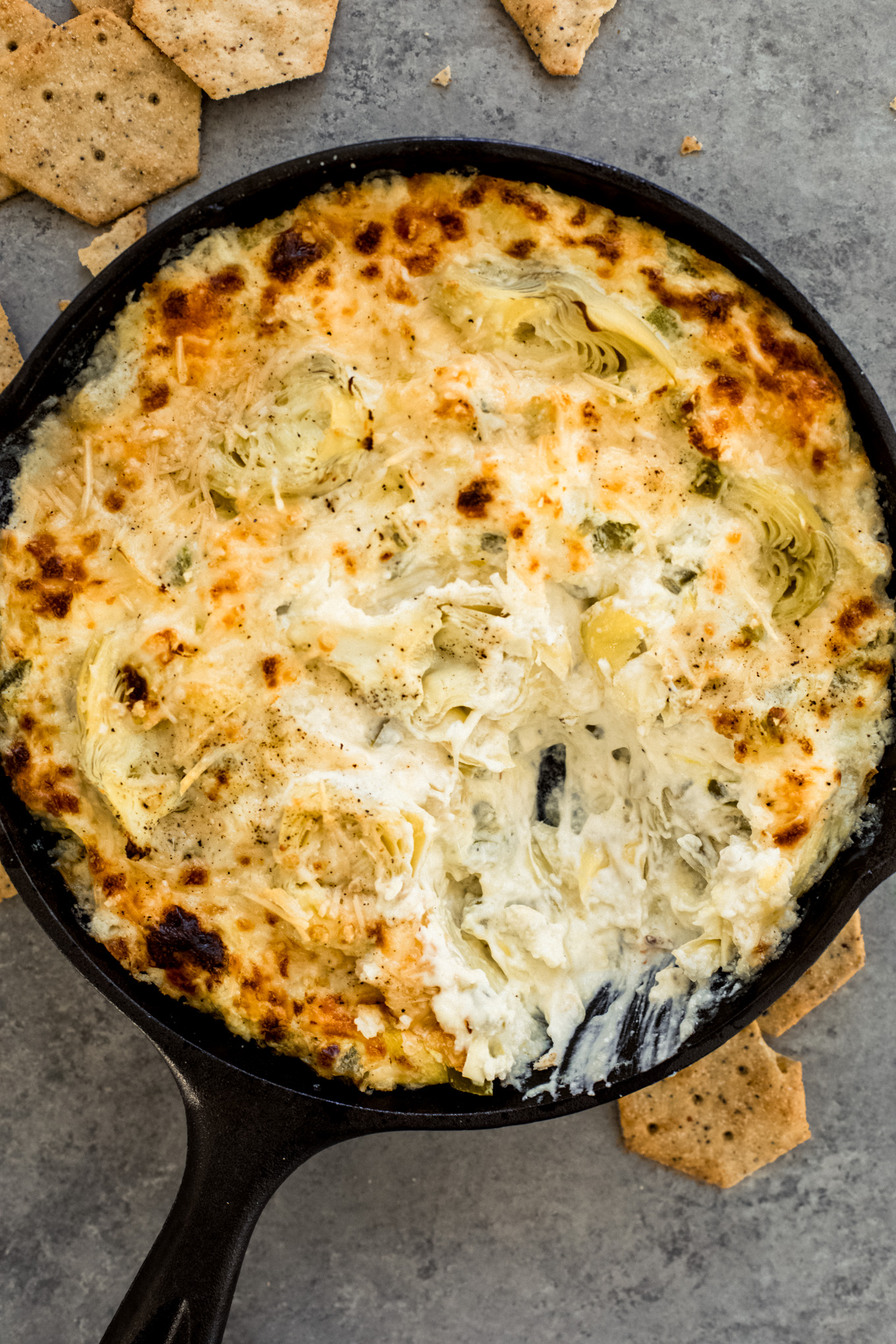 baked artichoke dip in a cast iron skillet.