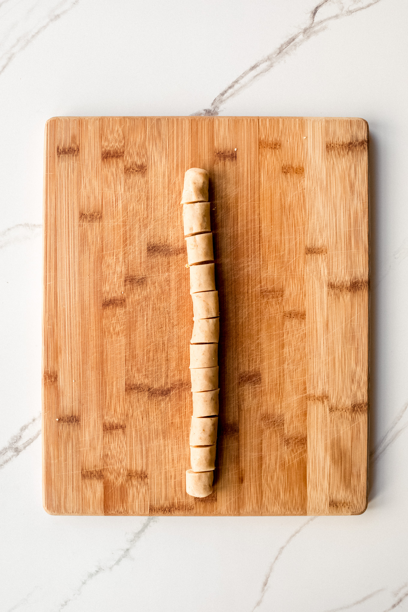 dough formed into a rope on a wooden board.