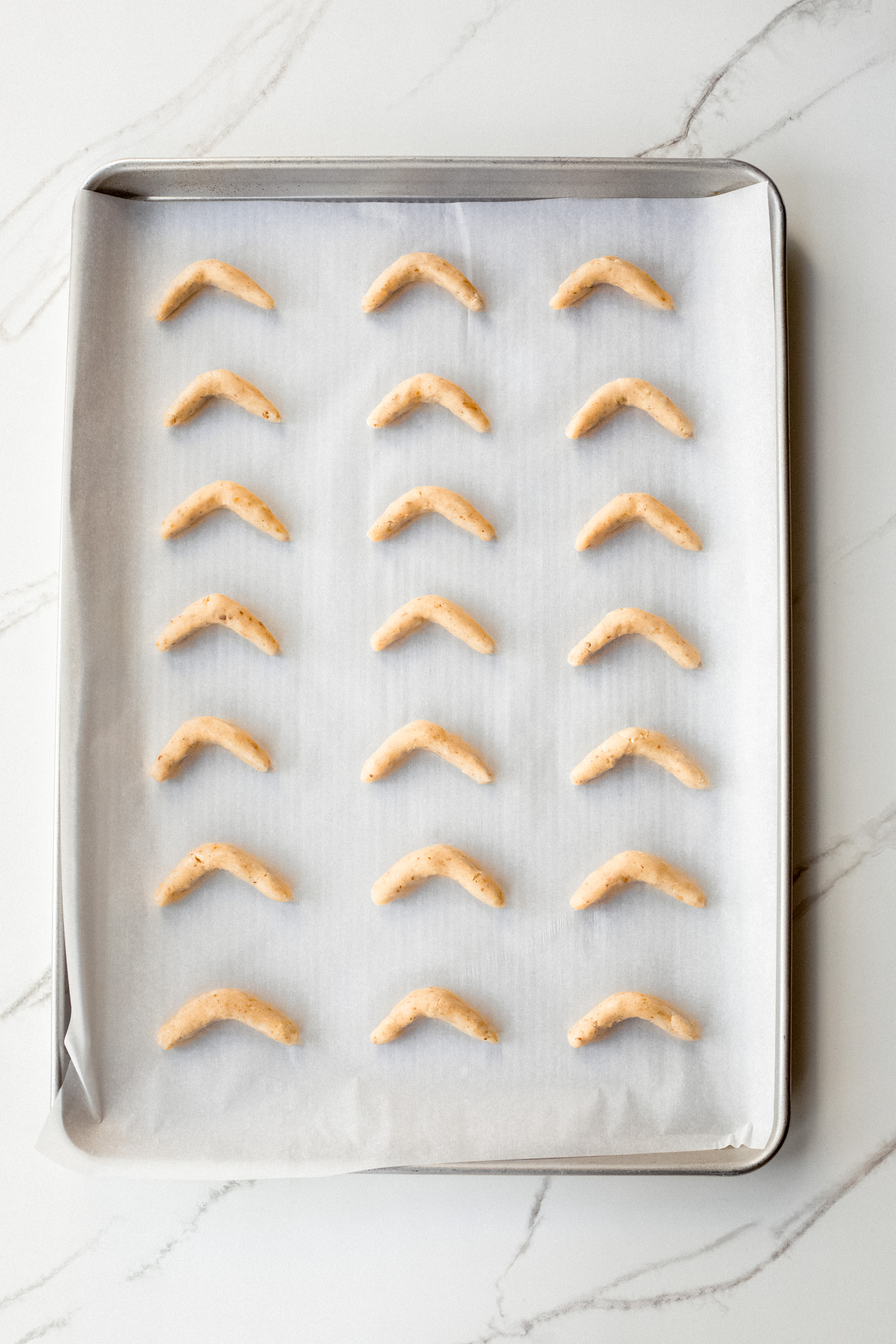dough formed into crescents on a baking sheet.