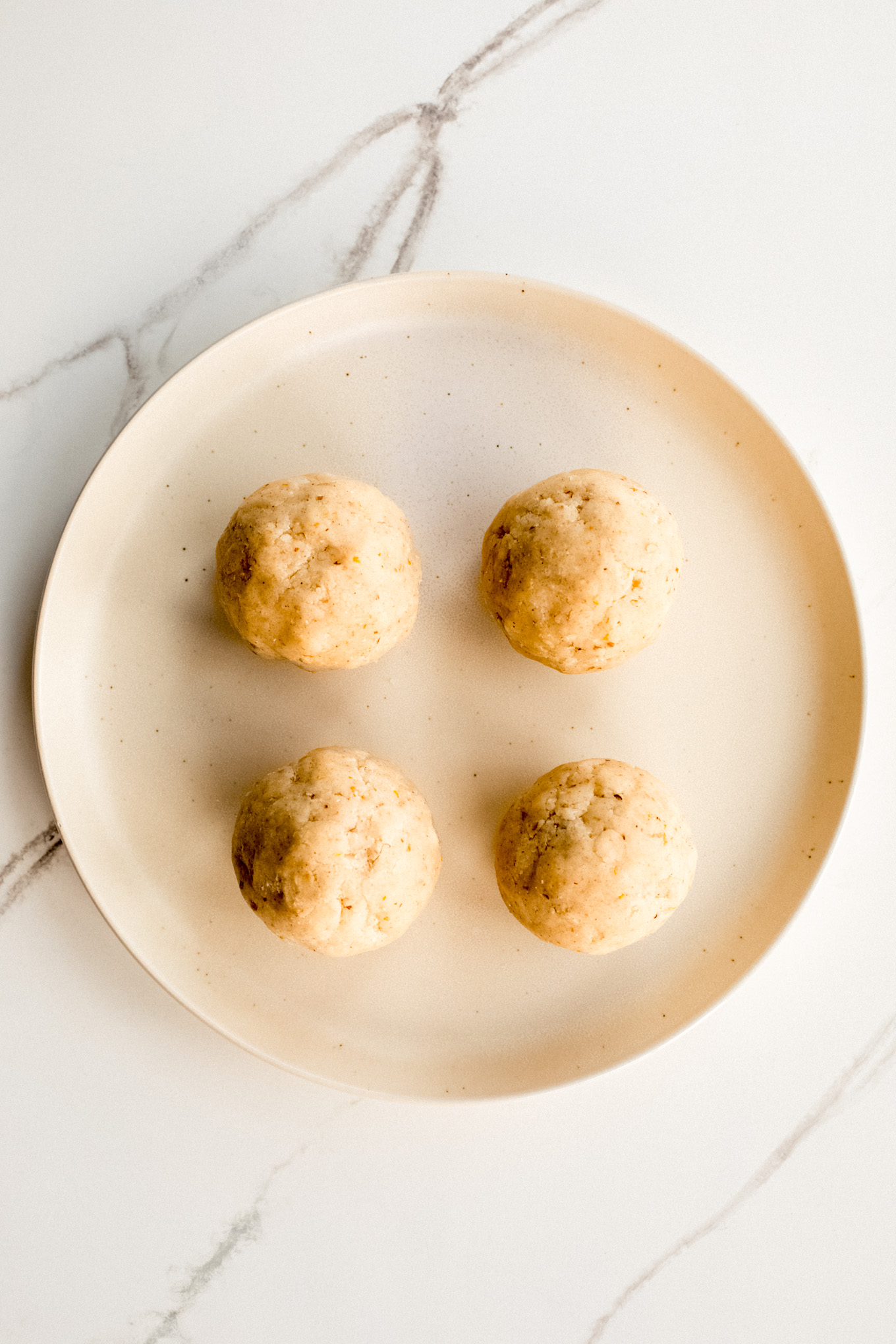 dough formed into four balls on a plate.