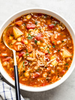 white bowl with vegetable soup and a side of a spoon.