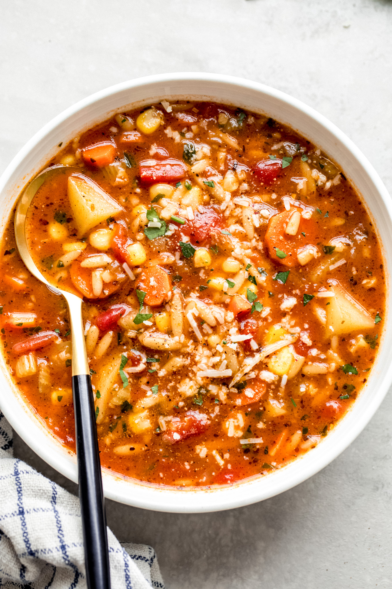 white bowl with vegetable soup and a side of a spoon.