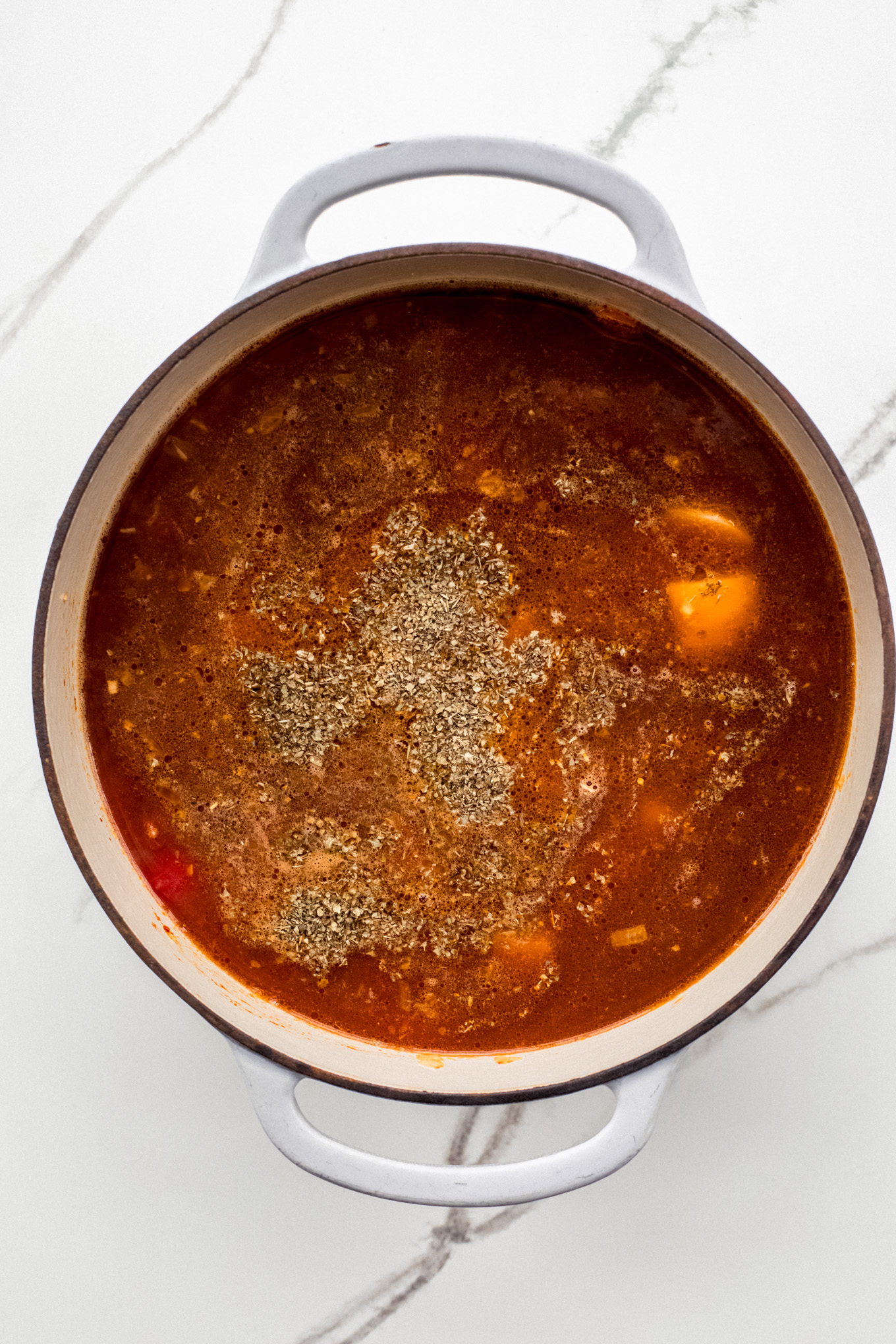 tomatoes and broth with vegetables in a soup pot.