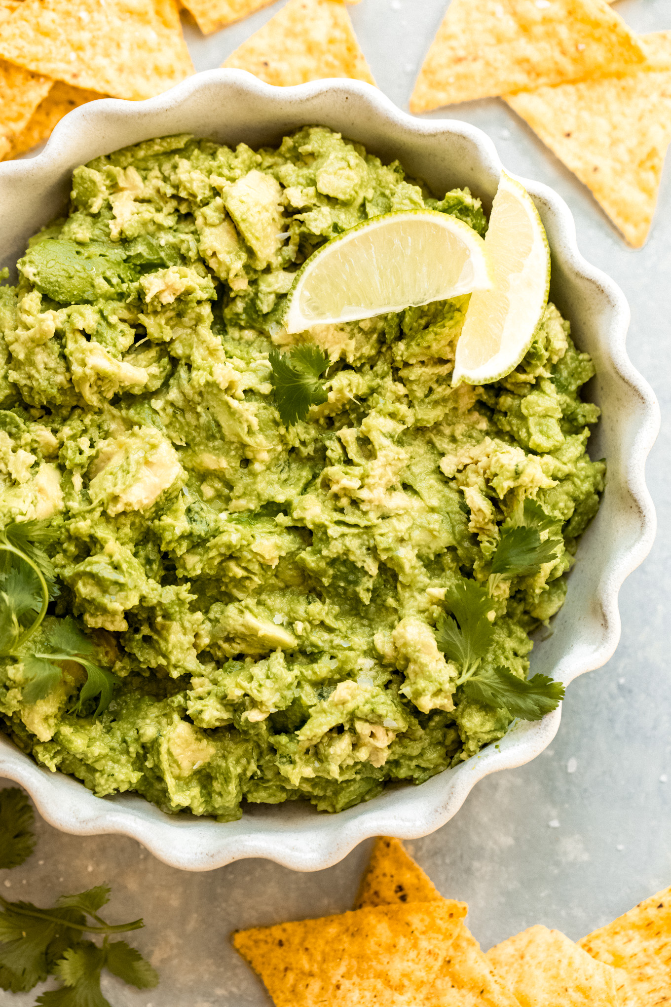 close up of prepared guacamole recipe in a bowl topped with limes.