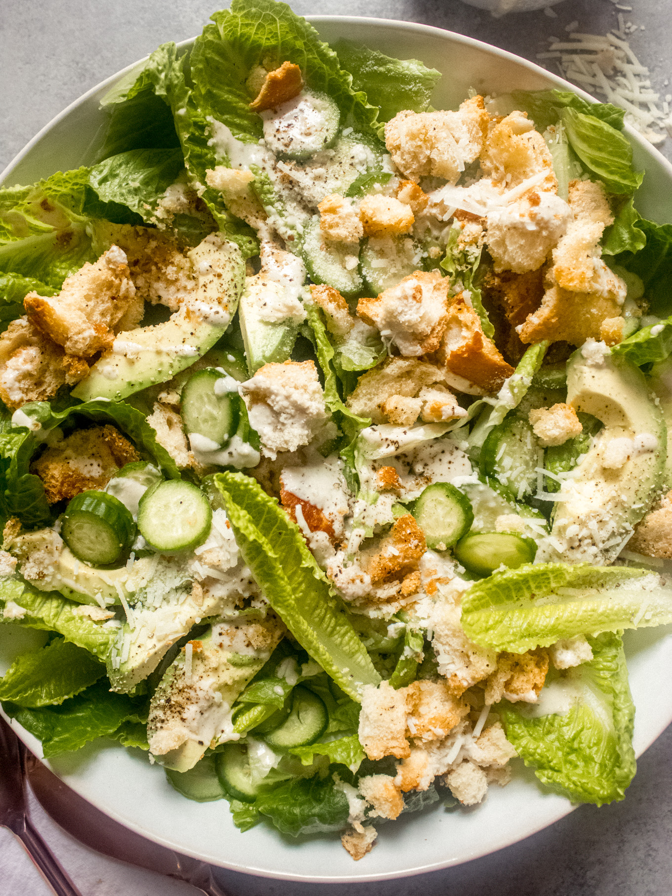close up of Caesar salad topped with Parmesan and dressing.