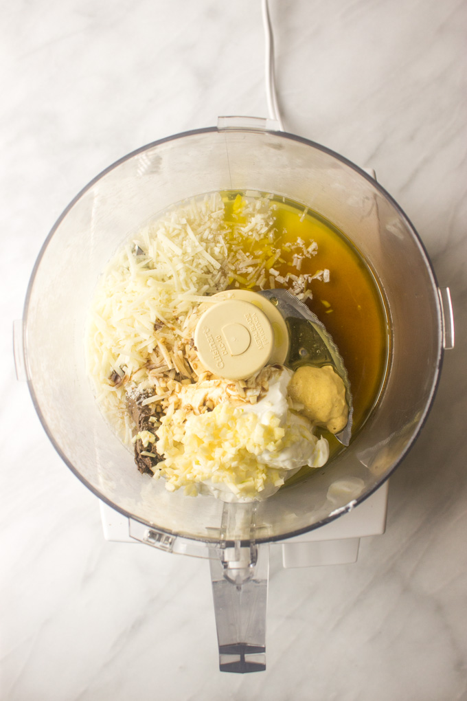 ingredients for Caesar dressing in a bowl of a food processor.