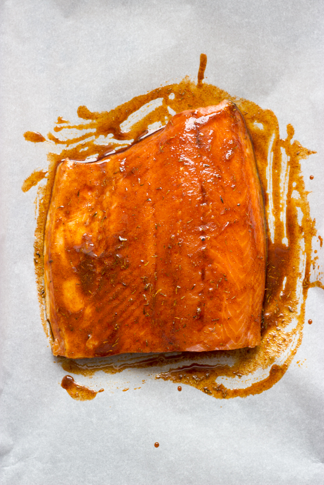 salmon with spice mixture rub on a baking sheet.