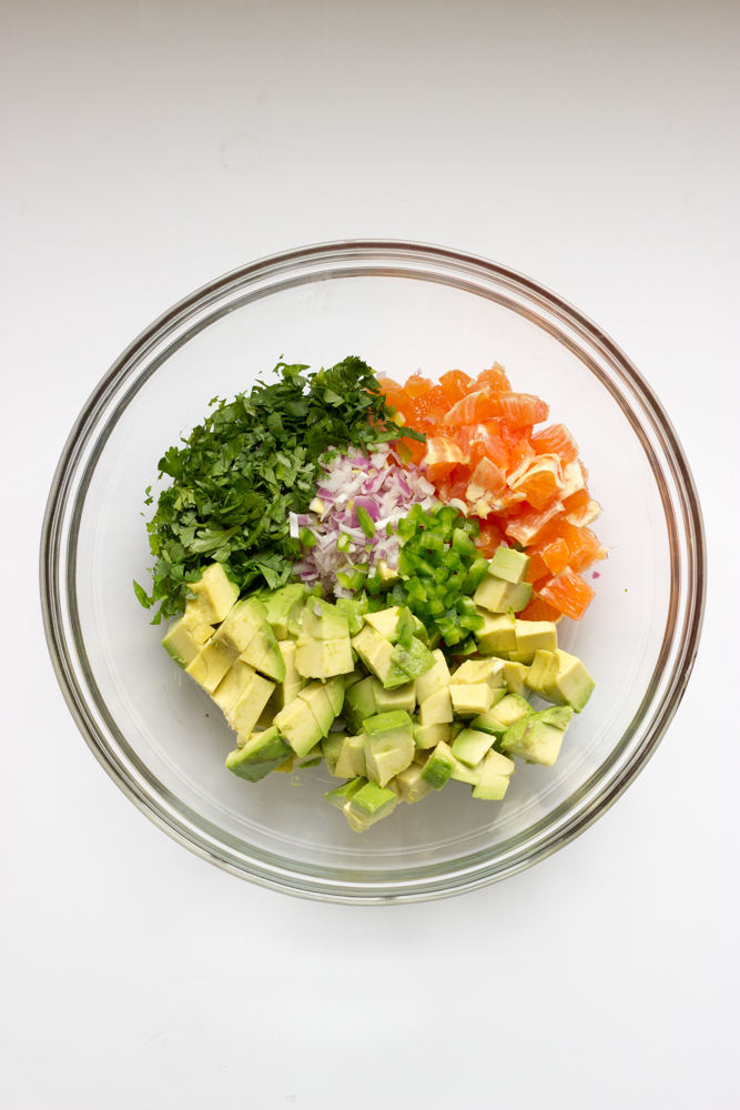 chopped avocado, orange, and cilantro in a glass bowl.