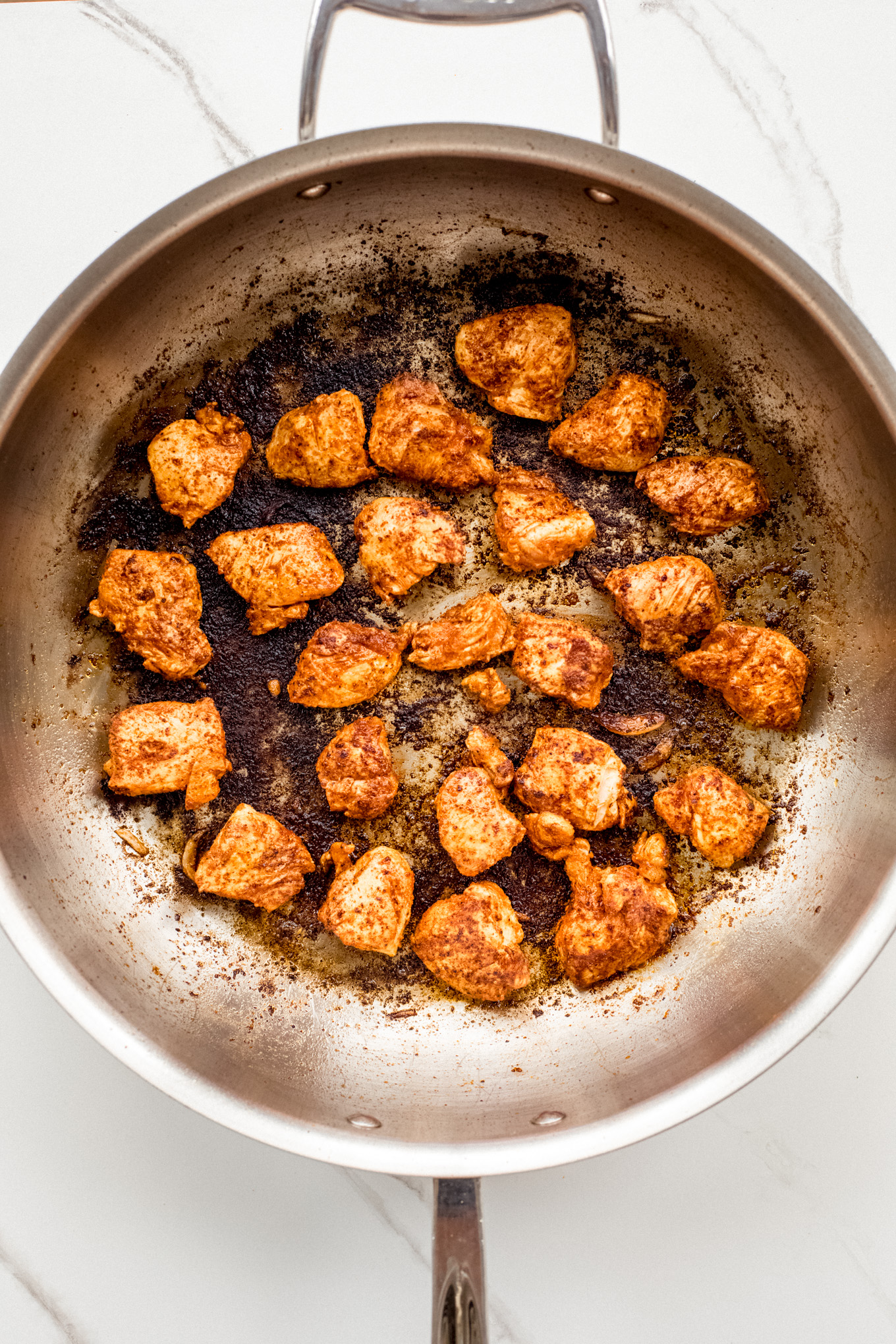 cooked chicken pieces in a saute pan.