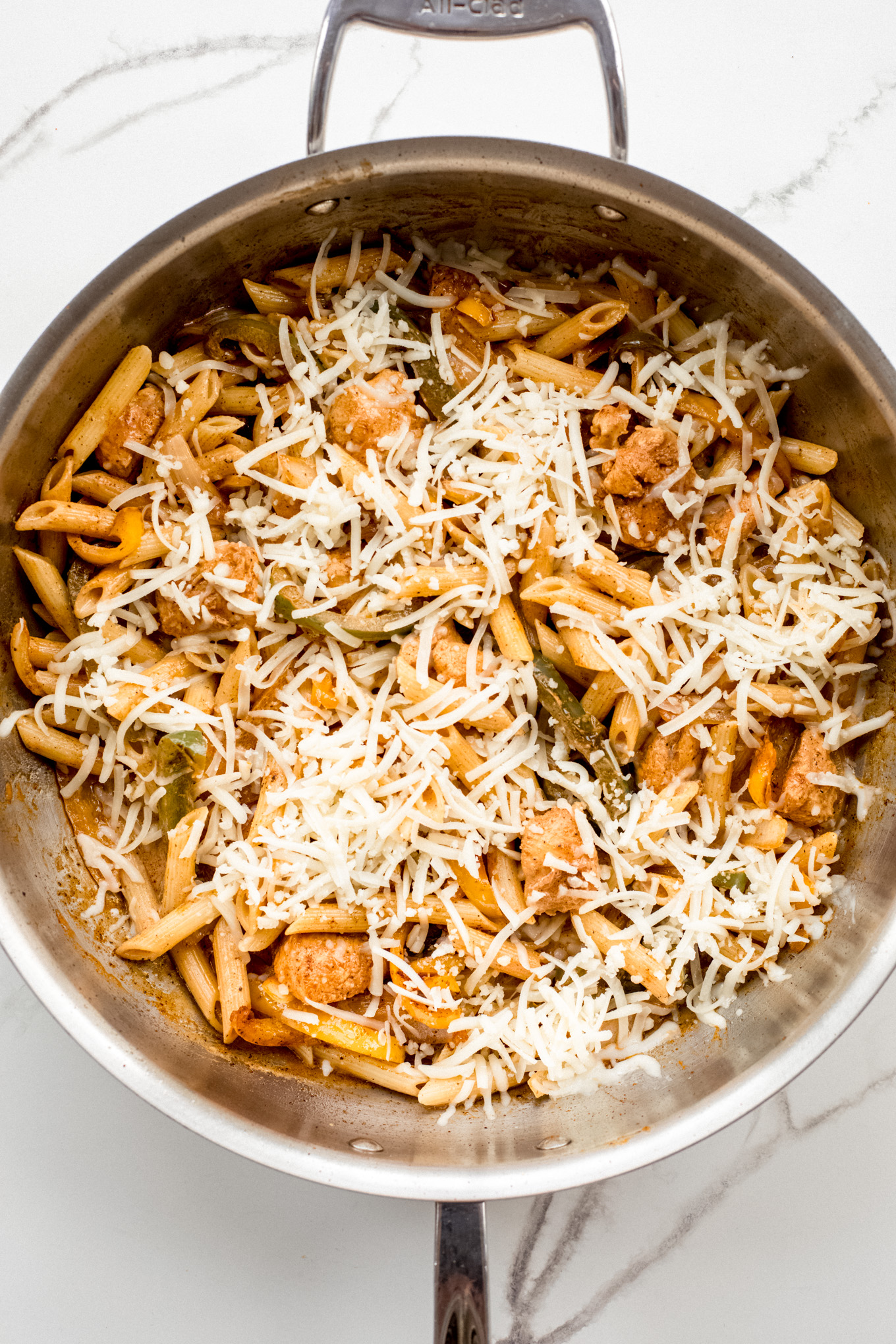 pasta with chicken and peppers topped with shredded cheese.