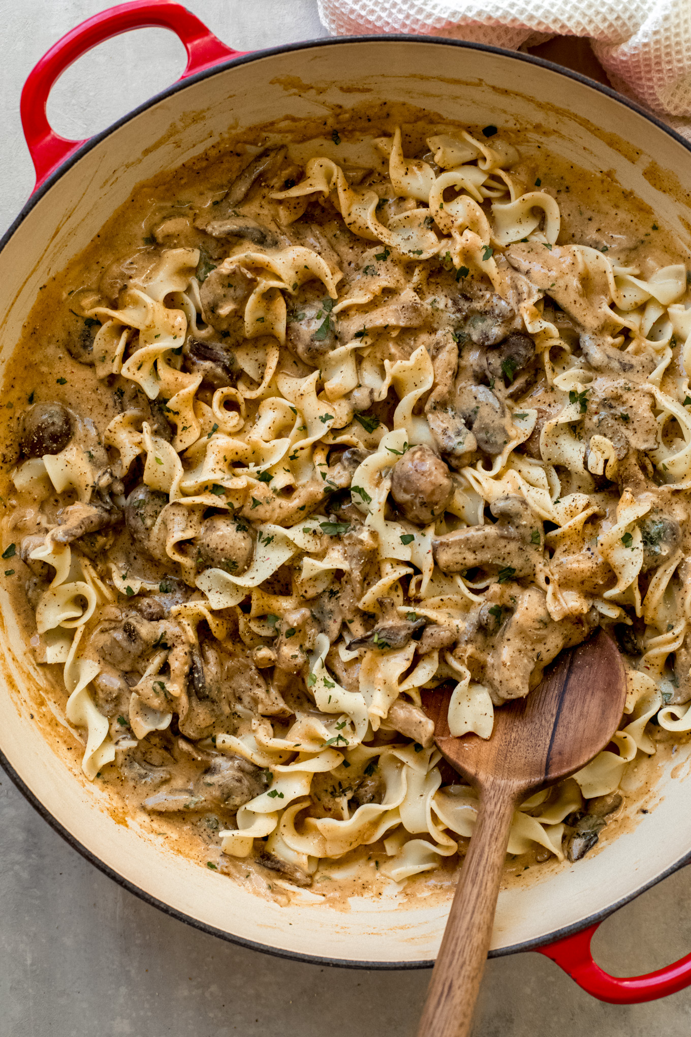 cooked egg noodles with mushroom sauce in a saute pan.