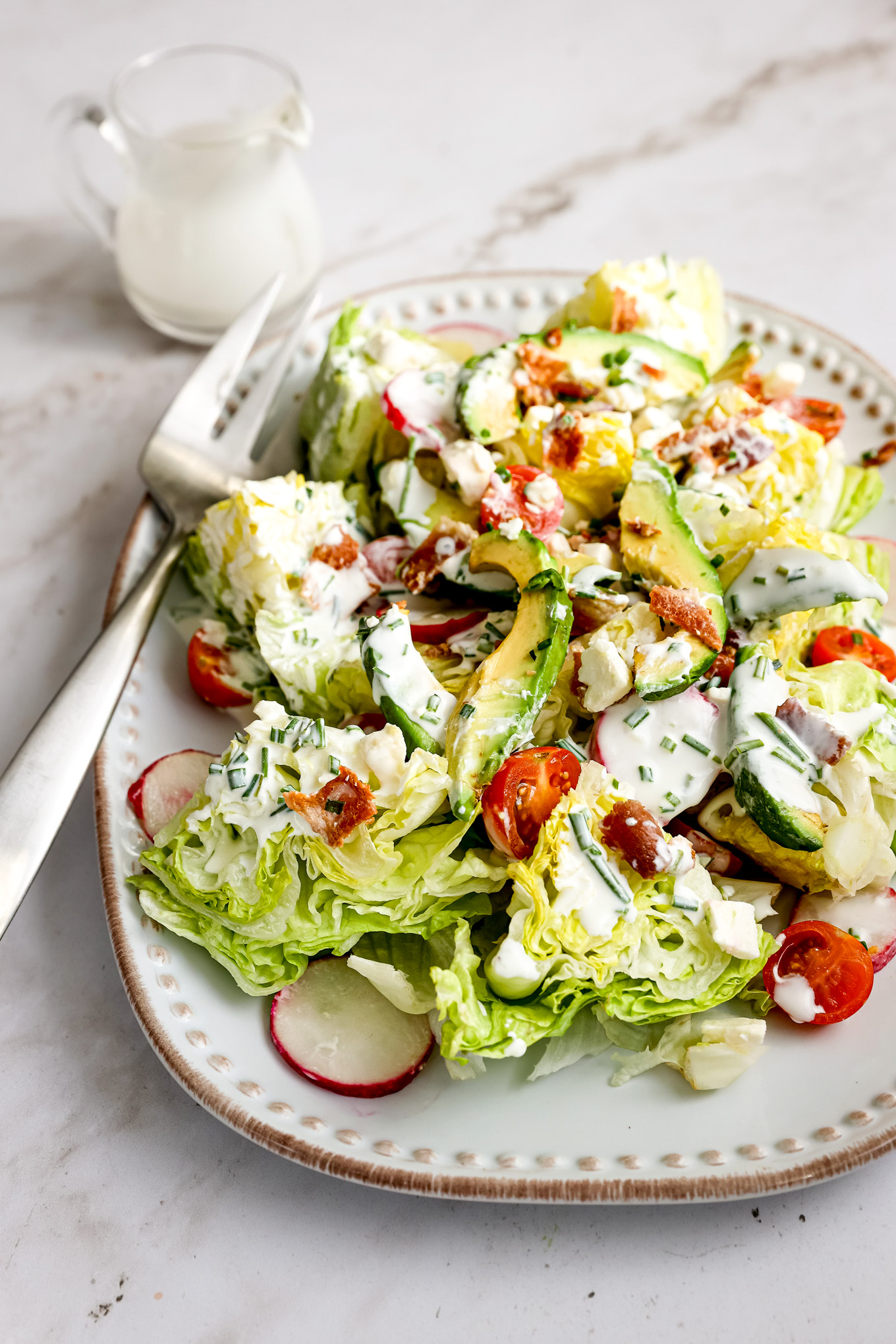 Chopped iceberg lettuce salad with tomatoes, radishes, and bacon.