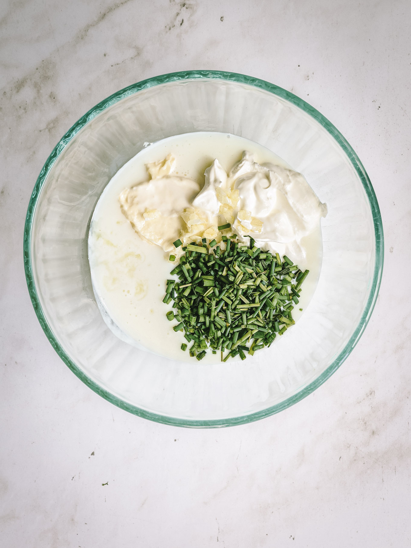 buttermilk, mayo, sour cream, and chives in a glass bowl.