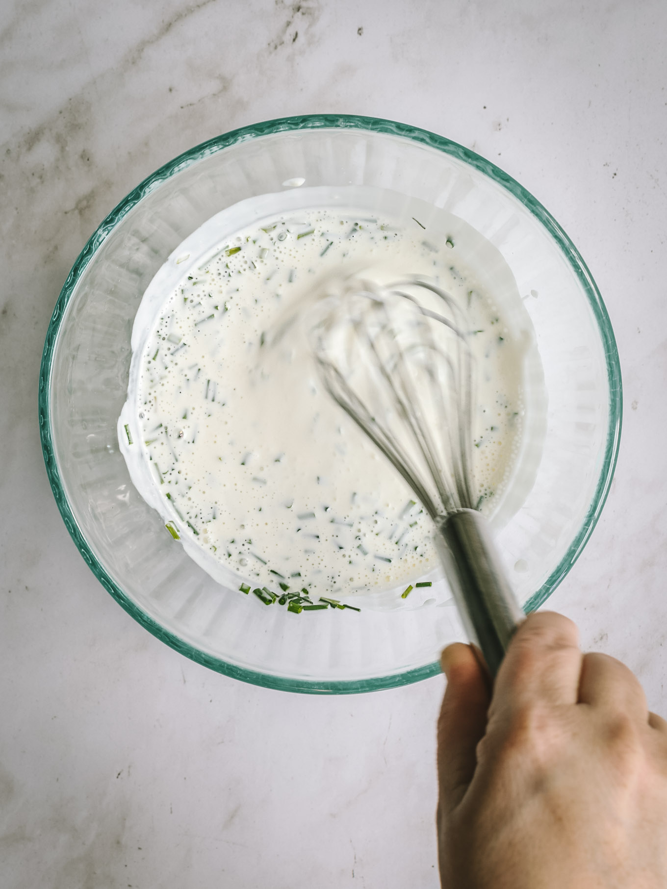 whisked buttermilk dressing in a glass bowl with a whisk.