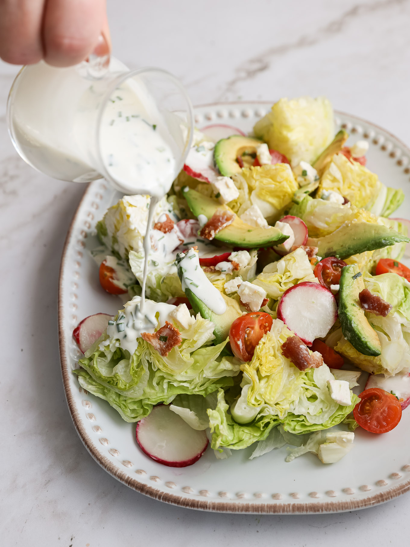 iceberg lettuce salad with buttermilk dressing being poured.