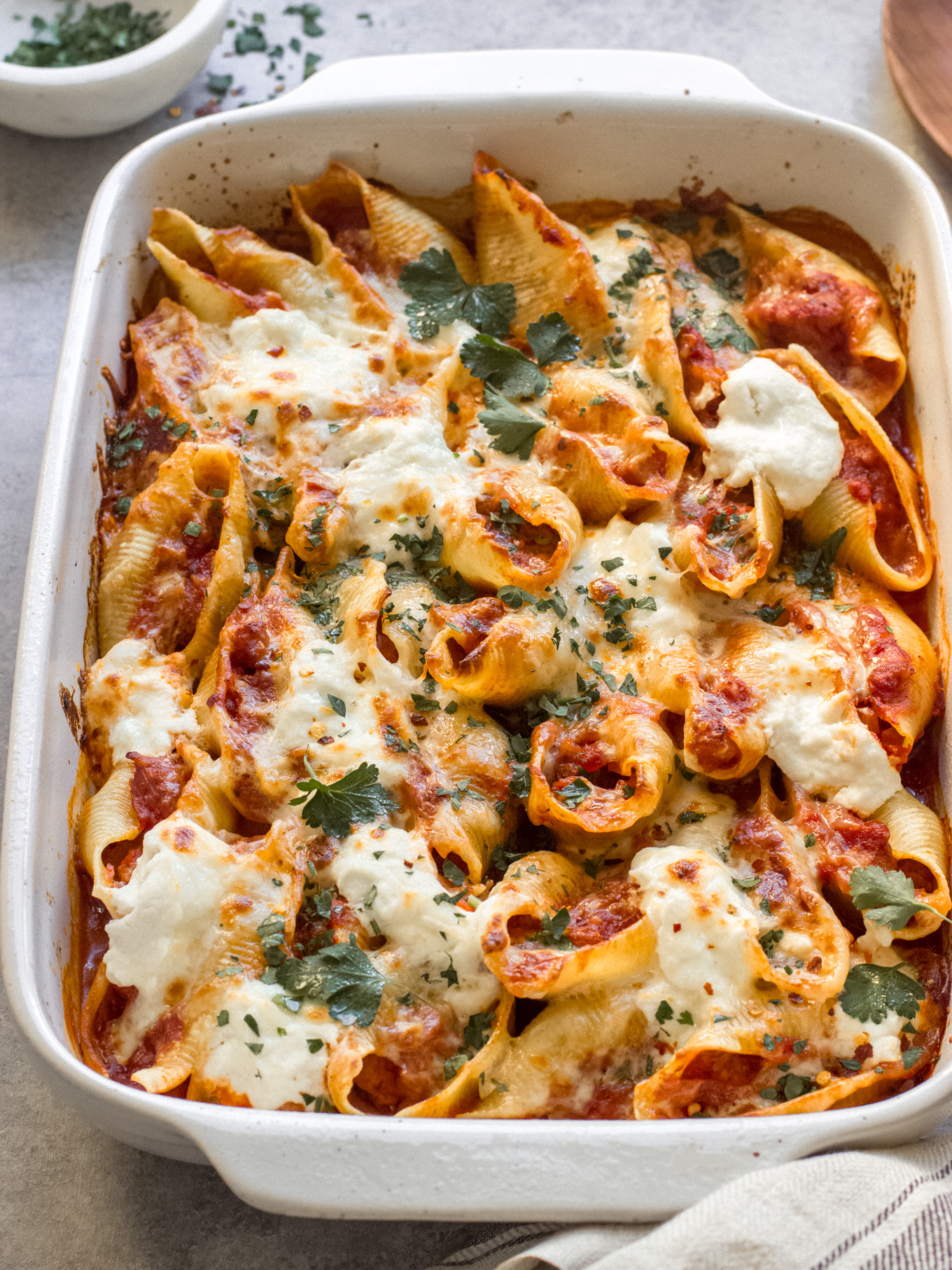 stuffed sausage stuffed shells in a white baking dish.