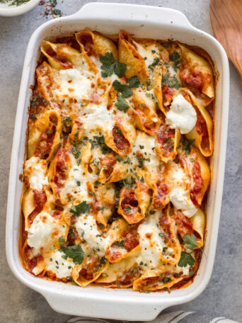 stuffed pasta shells with marinara and cheese in a baking dish.