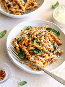 close up of pasta with spinach and sundried tomatoes topped with parmesan cheese.