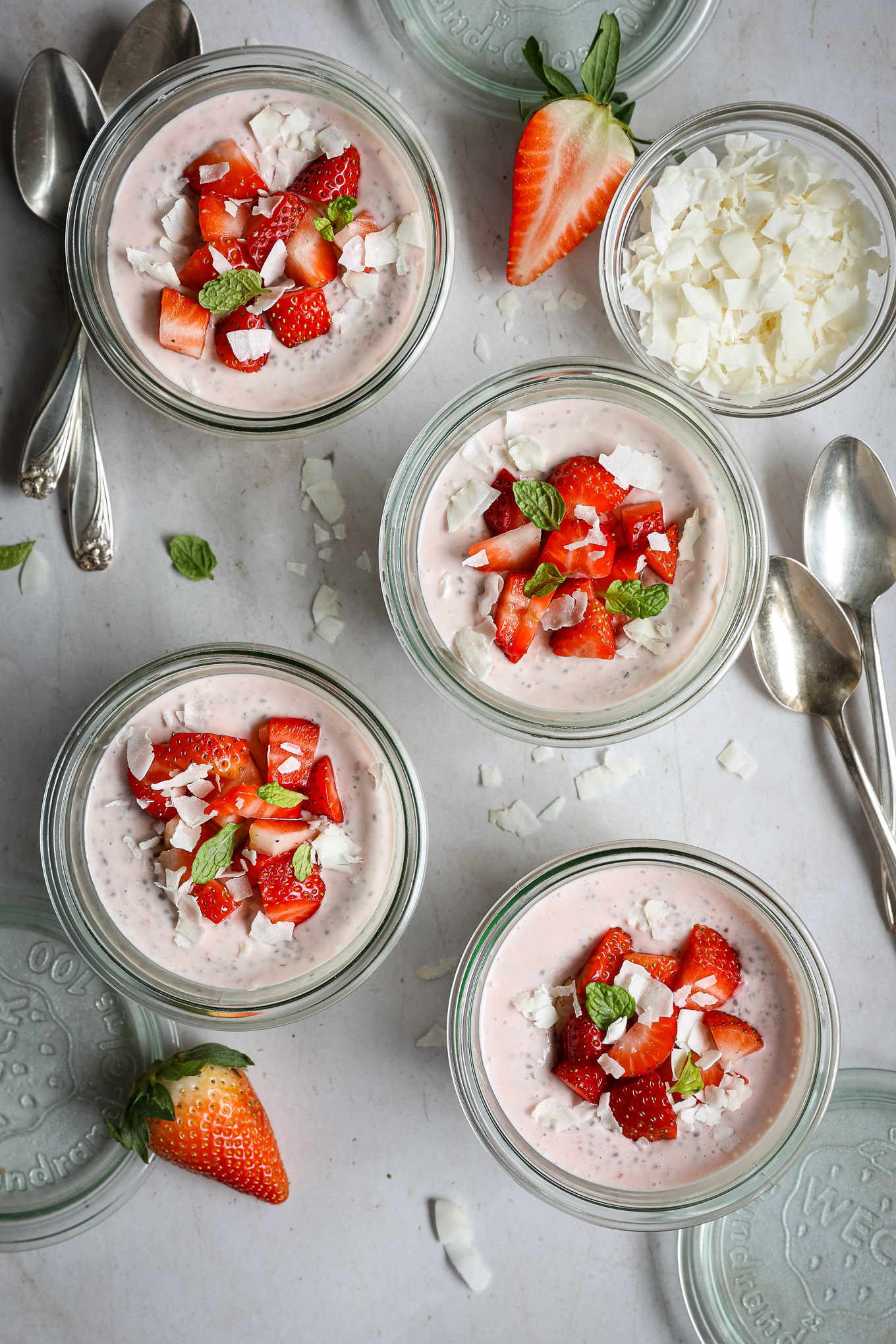 stawberry chia seed pudding in glass jars topped with fresh strawberries.