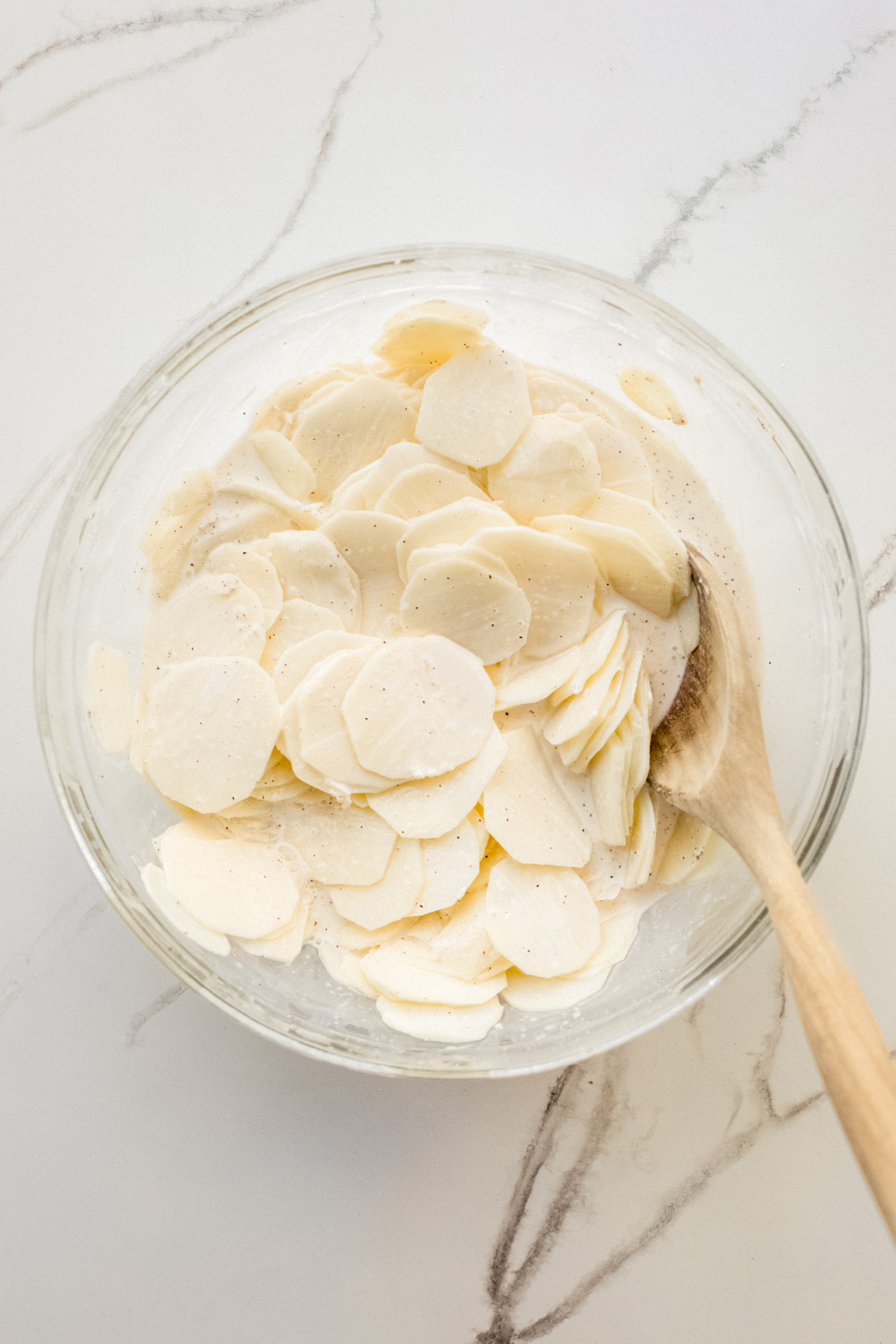 sliced potatoes in glass bowl with cream.