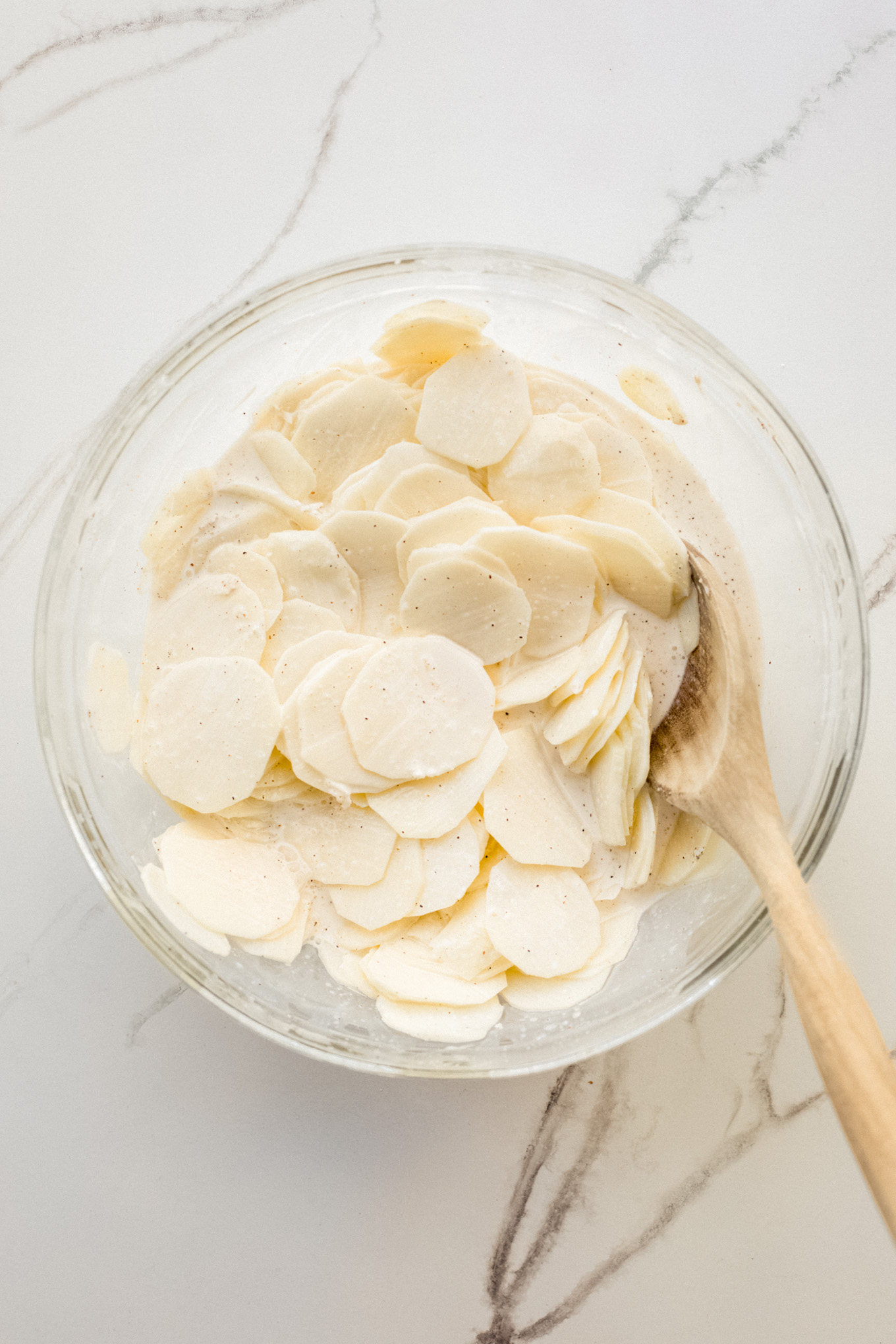 sliced potatoes in glass bowl with cream.
