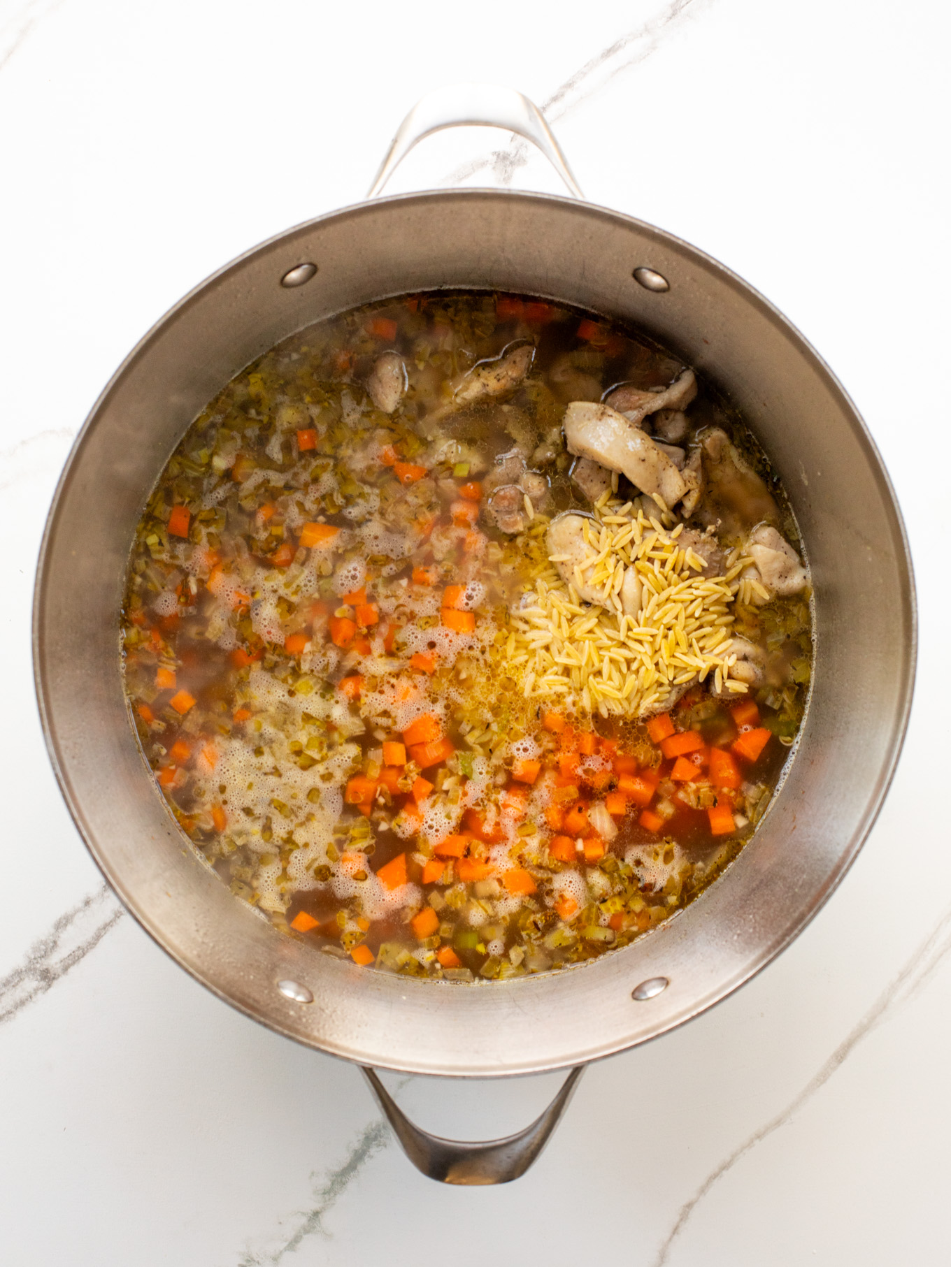 chicken and orzo in a dutch oven with chicken stock.