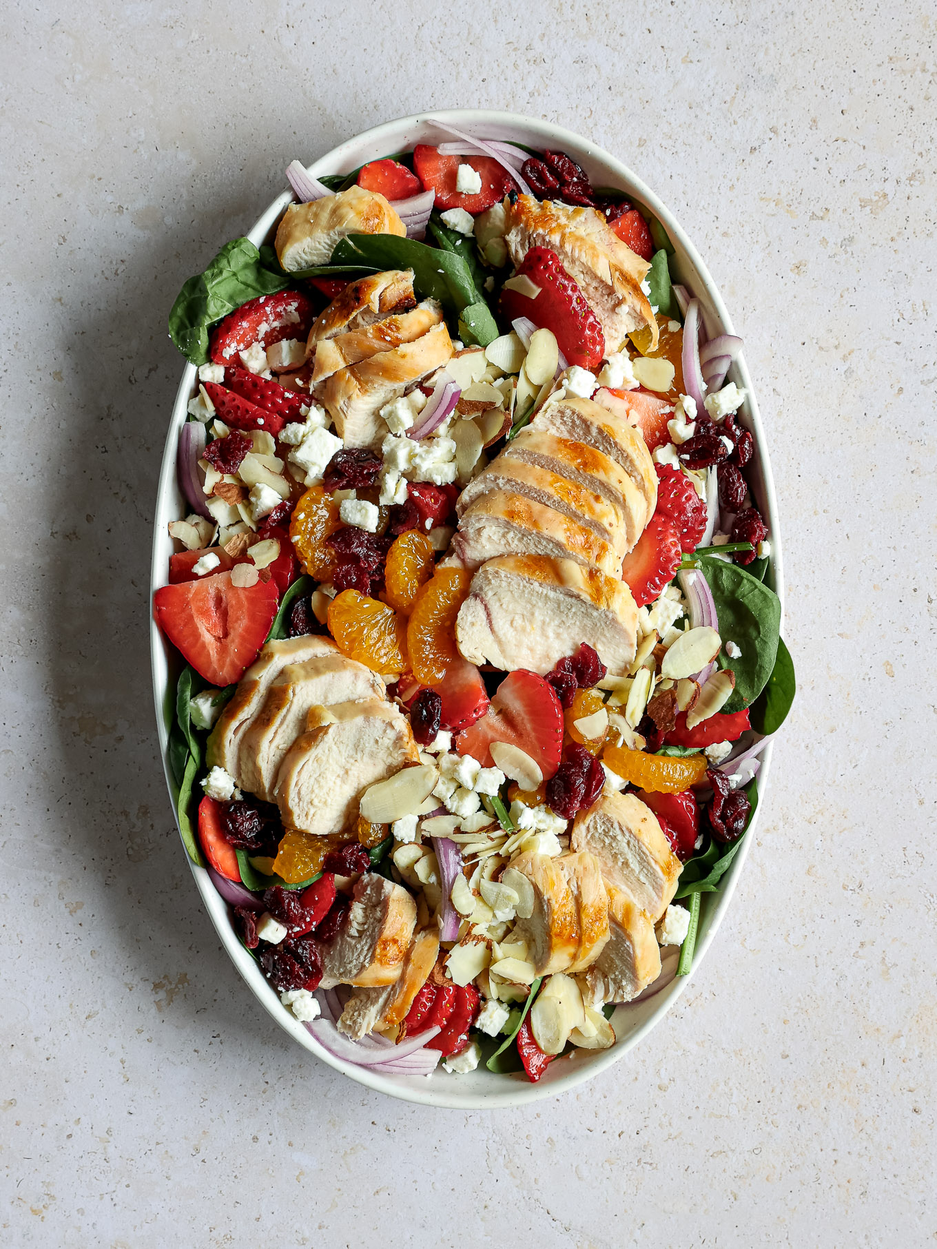 spinach salad topped with grilled sliced chicken.