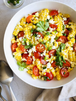 corn salad with tomatoes, feta, and cilantro in a white bowl.