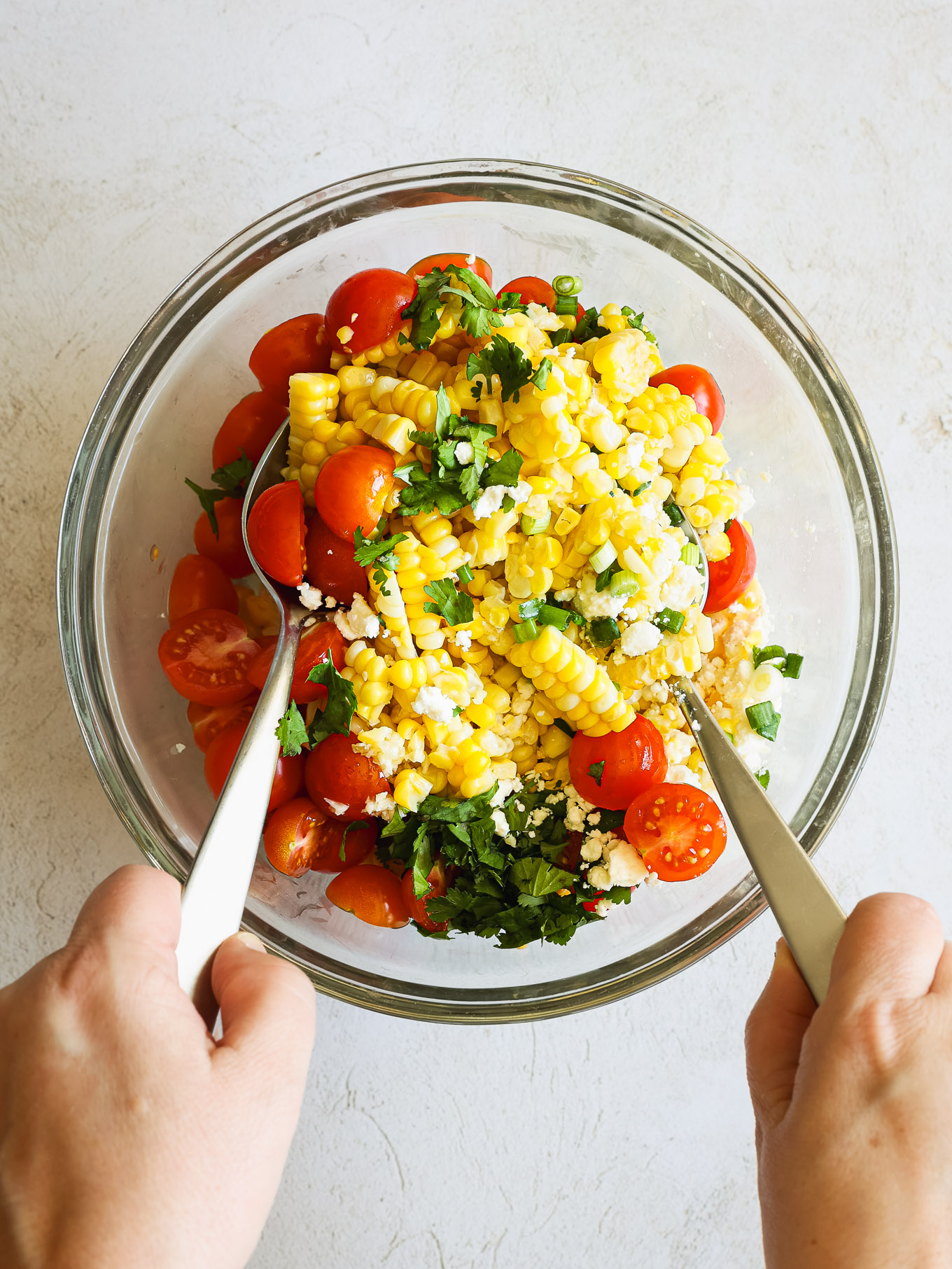 corn salad tossed with spoons.