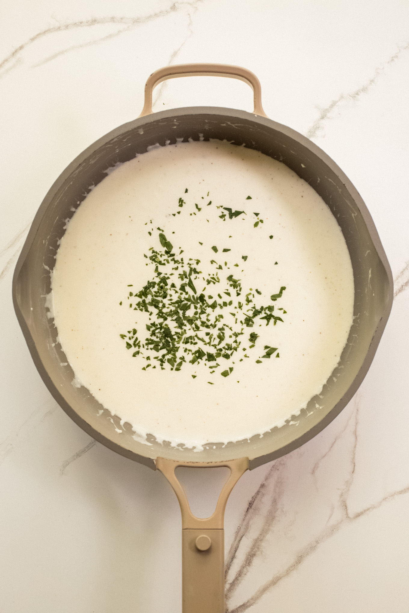 fresh chopped parsley over cream sauce in pan.